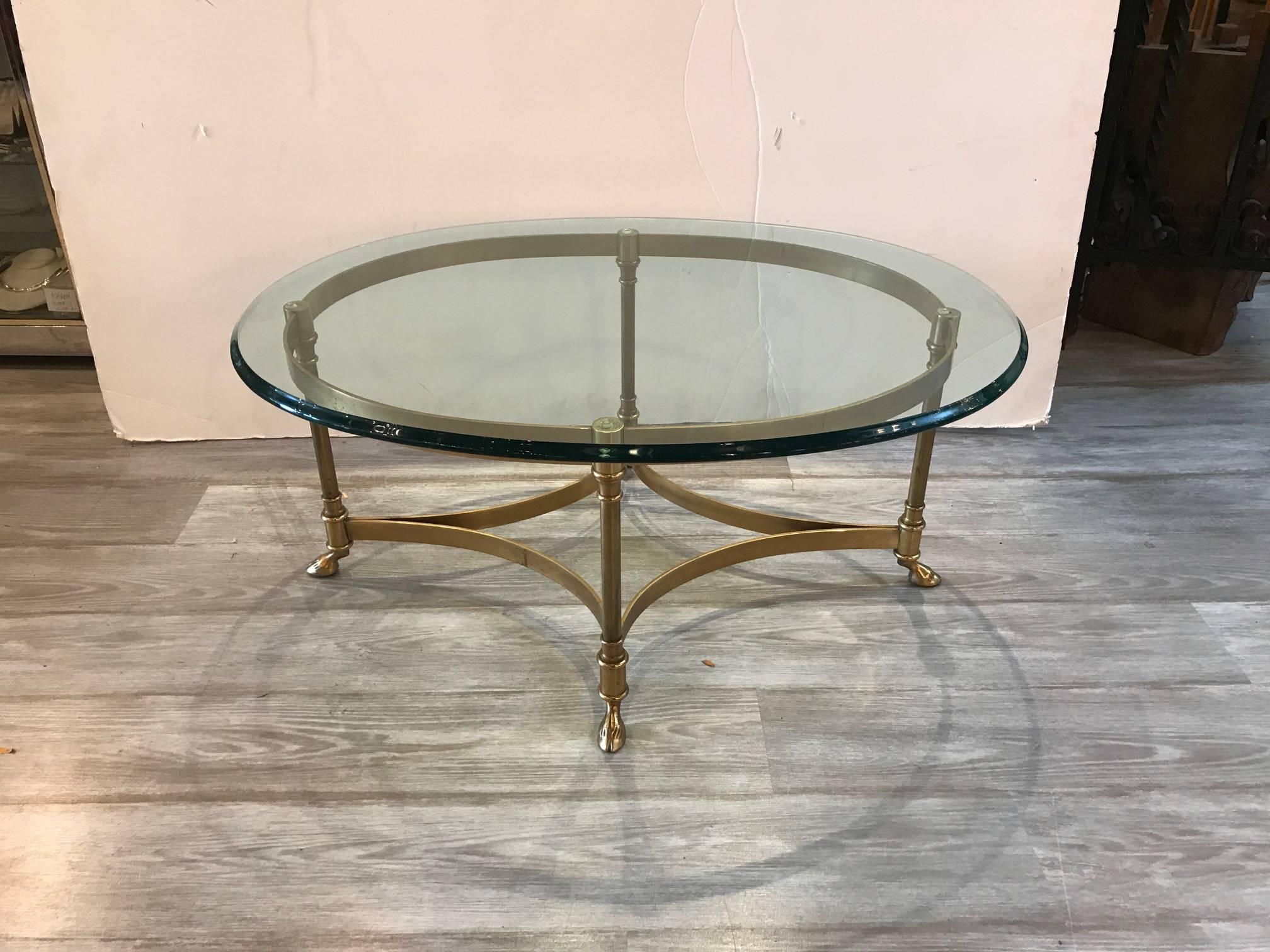 A Classic brass and glass cocktail table by Labarge with thick glass top and iconic hoof footed brass base. Rare diminutive size.