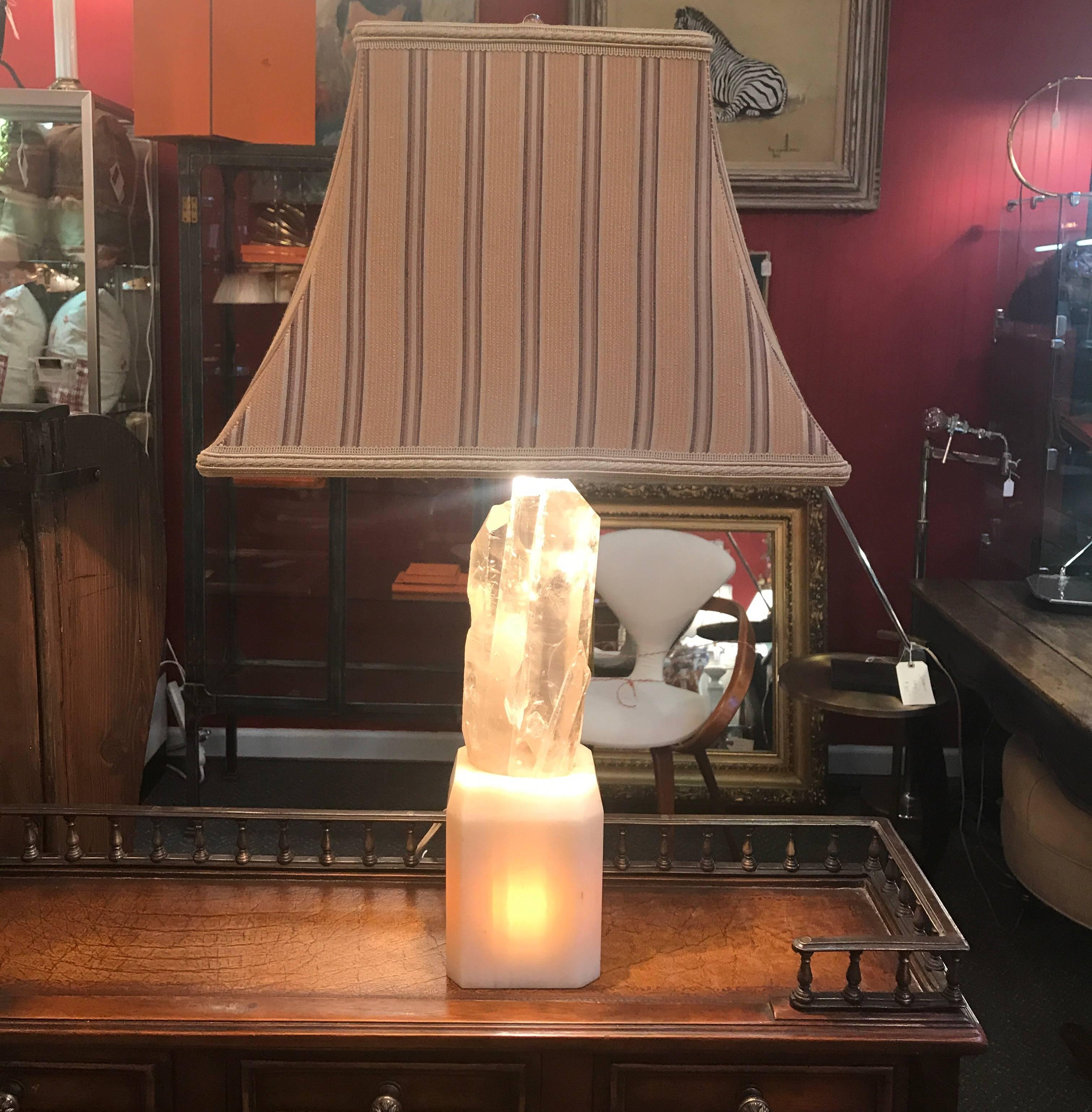 Chic natural rock crystal white quartz lamp with a white marble base. The natural rock crystal is removable from its custom marble base but fits snugly. This early 20th century lamp that also illuminates from the base with stripe all silk shade.