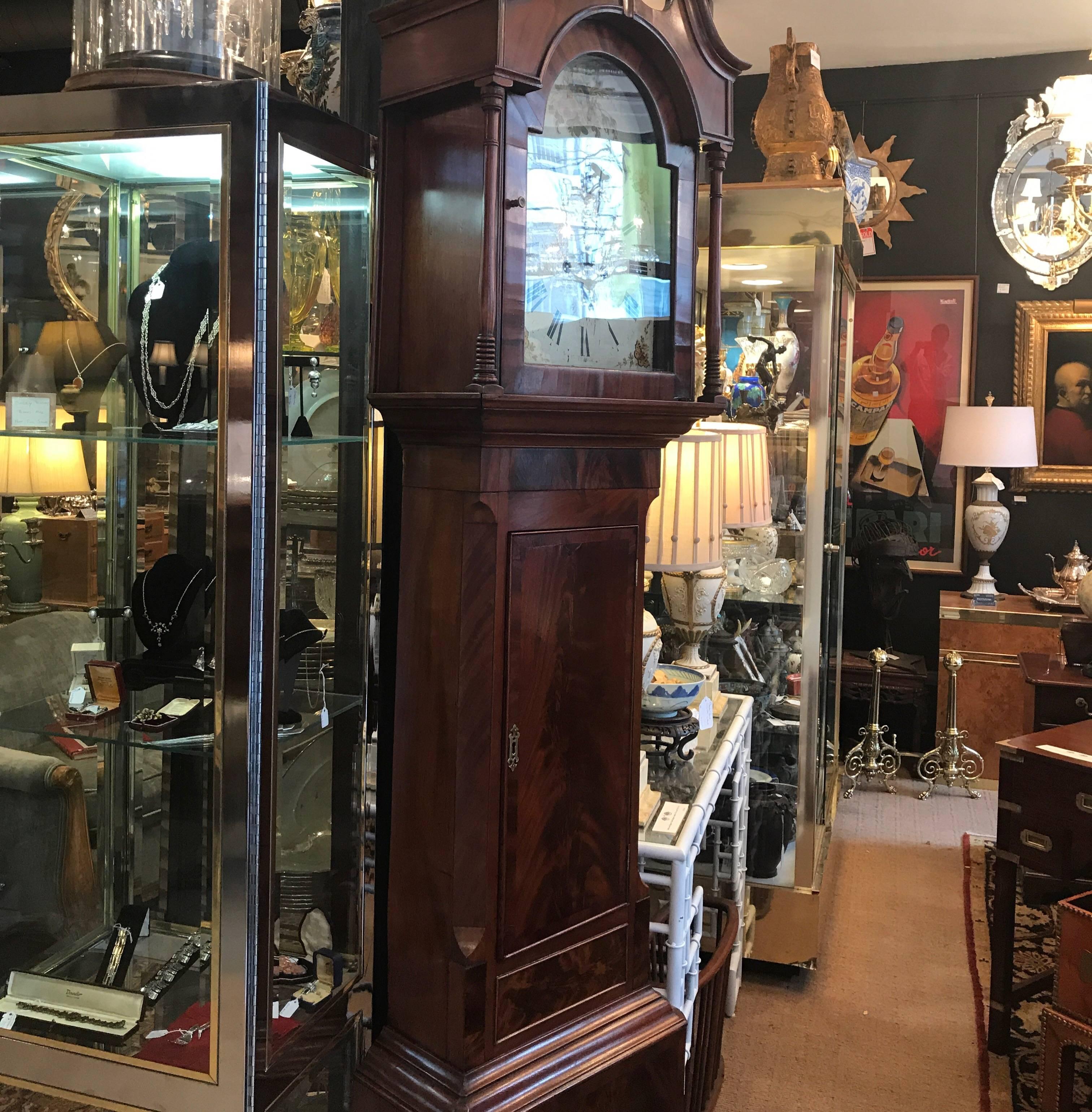 A George III mahogany tall case clock circa 1810-1820, signed John Blaylock. Blaylock came from three generations of clock makers. The case features a swans neck pediment over an arched glazed door flanked by turned columns opening to a white