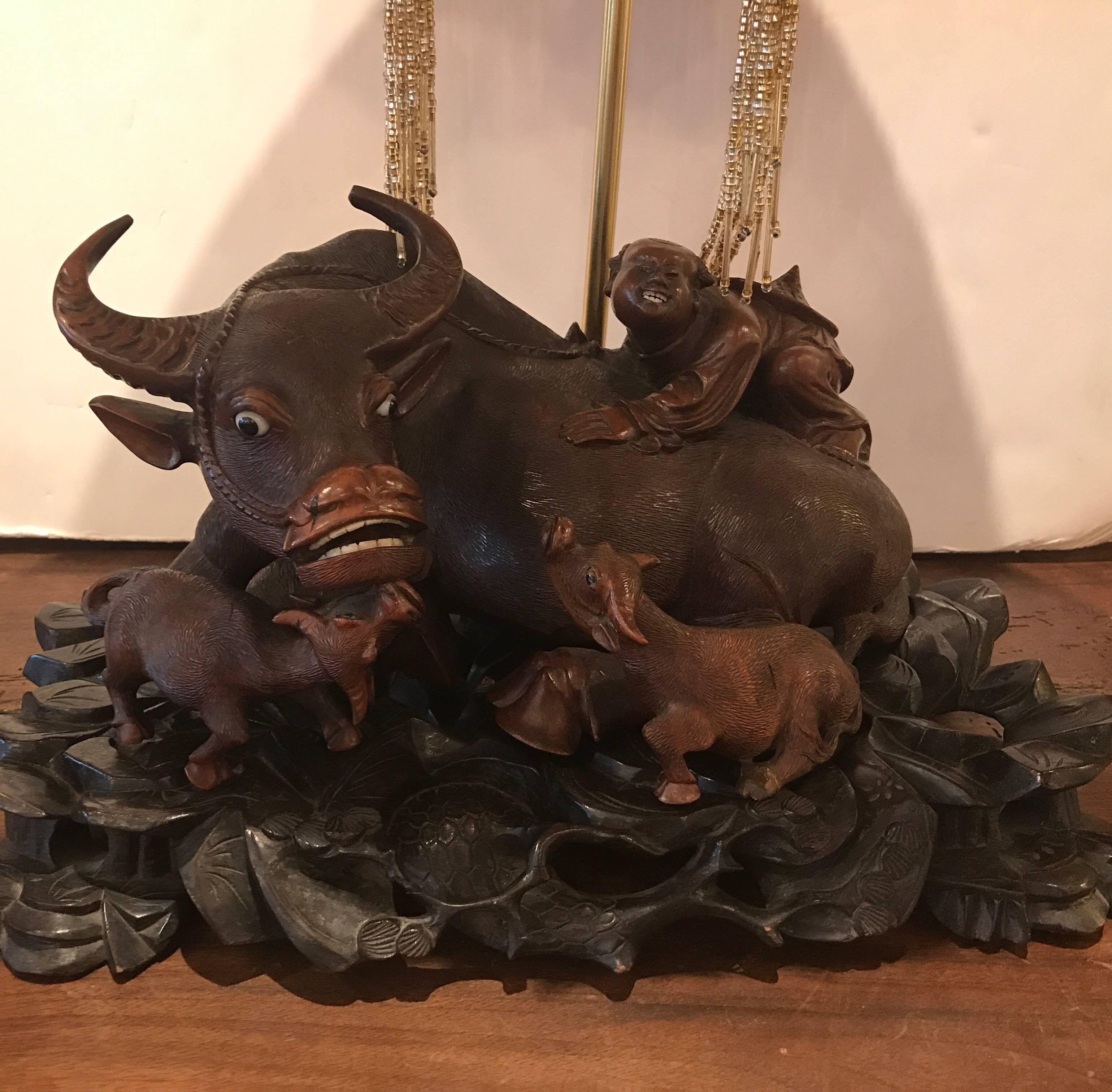 A hand-carved antique Meiji period figural lamp. The rosewood figures of water buffalo with a man riding on back, the sculpture rests on a hand-carved ebony base original to the piece. This sculpture was lamped later circa 1920 and retains its