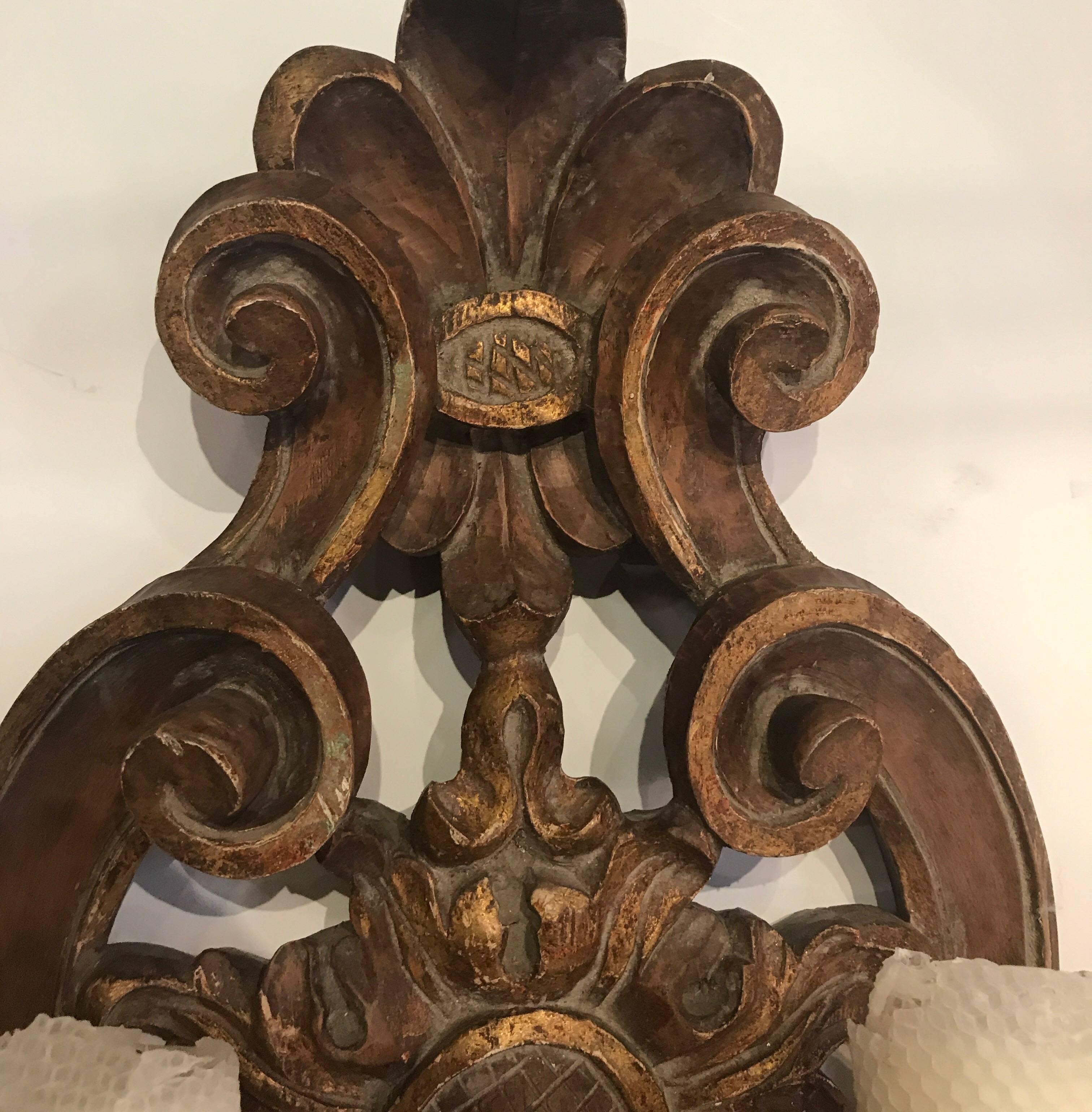 Exceptionally carved all wood and hand-forged iron arm sconces. These sconces are not wired for electricity. There are some original gilt accents showing some wear but all original.