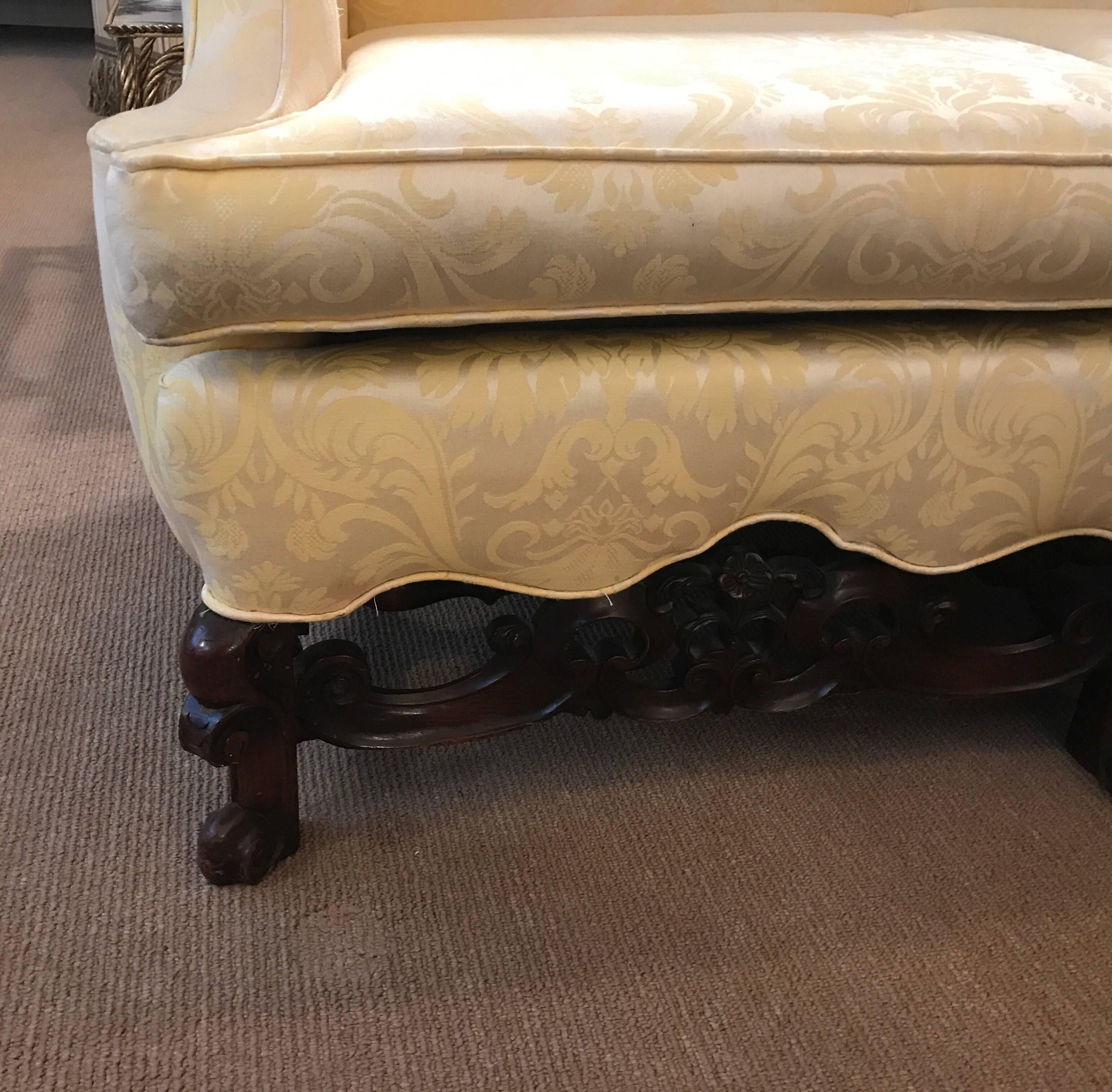 Stately antique tight back sofa with hand-carved walnut base. The clean back with shapely arms and a scalloped apron resting on carved English Jacobean style legs with stretchers. This sofa is a great apartment size, 78 inches long. The springs are