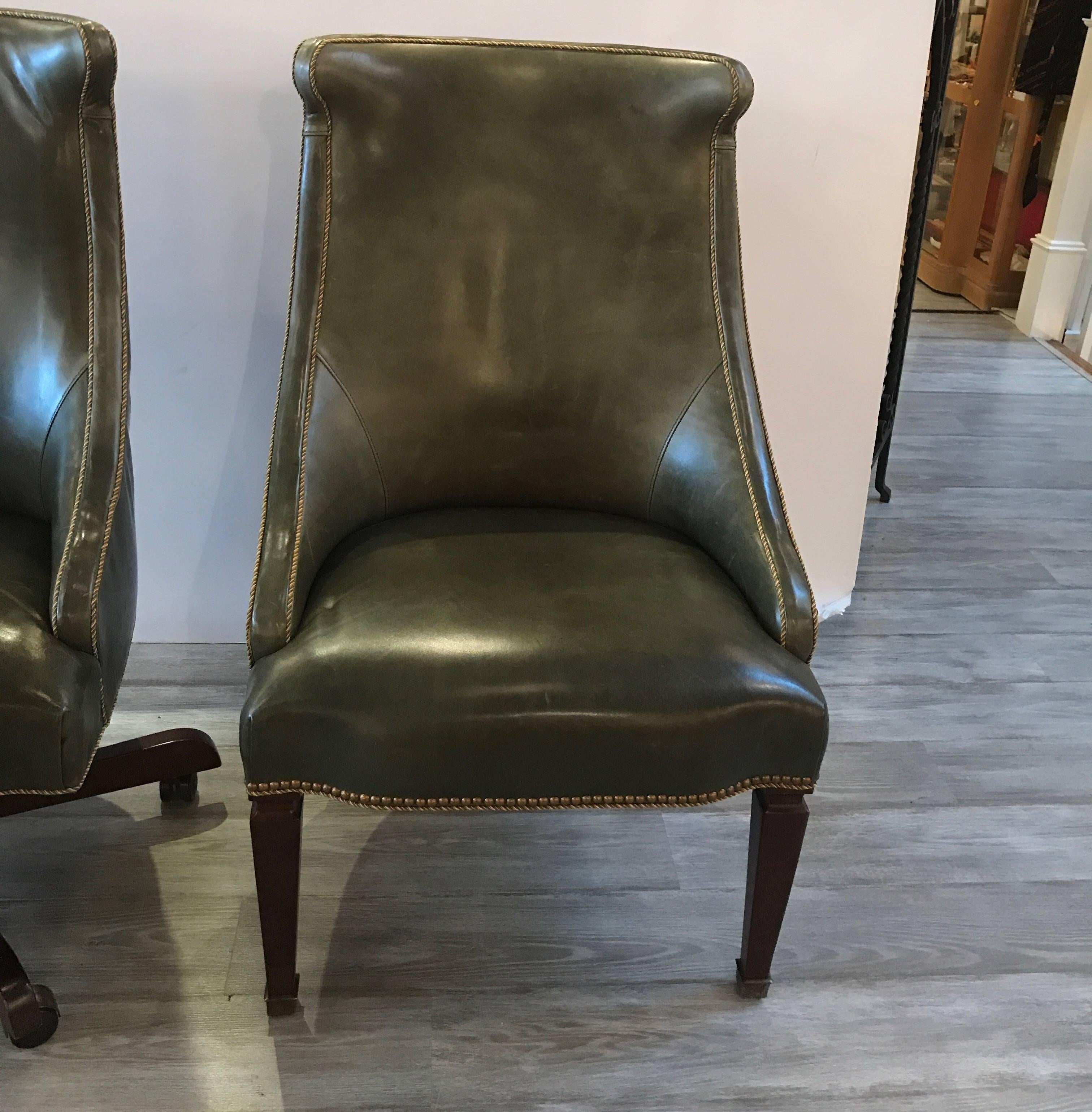 A stylish pair of leather chairs, one is a swivel base the other is stationary. Intended to be used along a desk. The swivel desk chair with corded trim and the stationary side chair with nail head and corded trim. Both chairs are upholstered in a