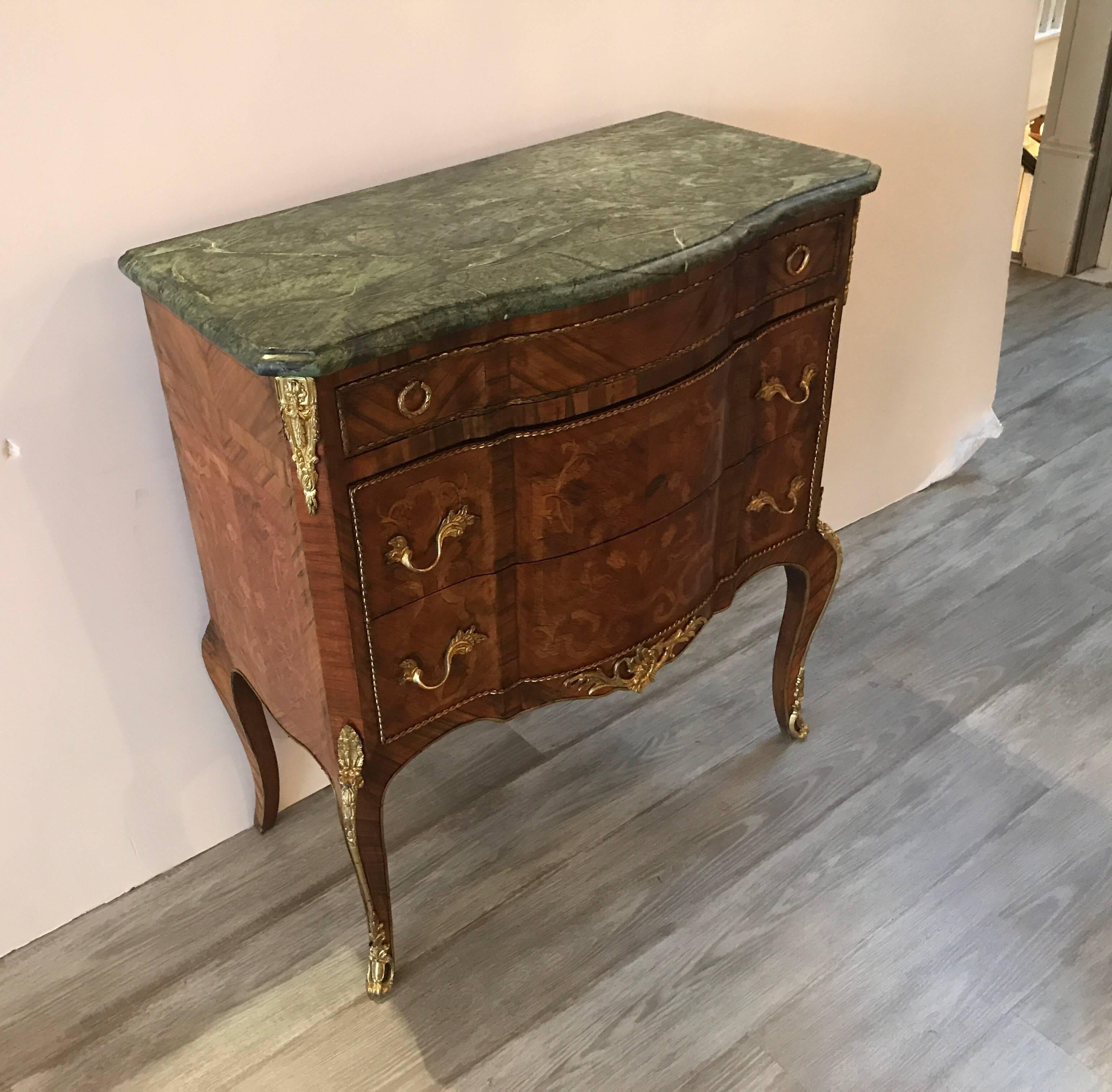 A rare smallish pair of French inlaid commodes with rich olive green marble tops. Three drawers with inlaid fronts of kings wood and tulip wood. The commodes are 29 inches wide and perfect as side accent chests or nightstands.