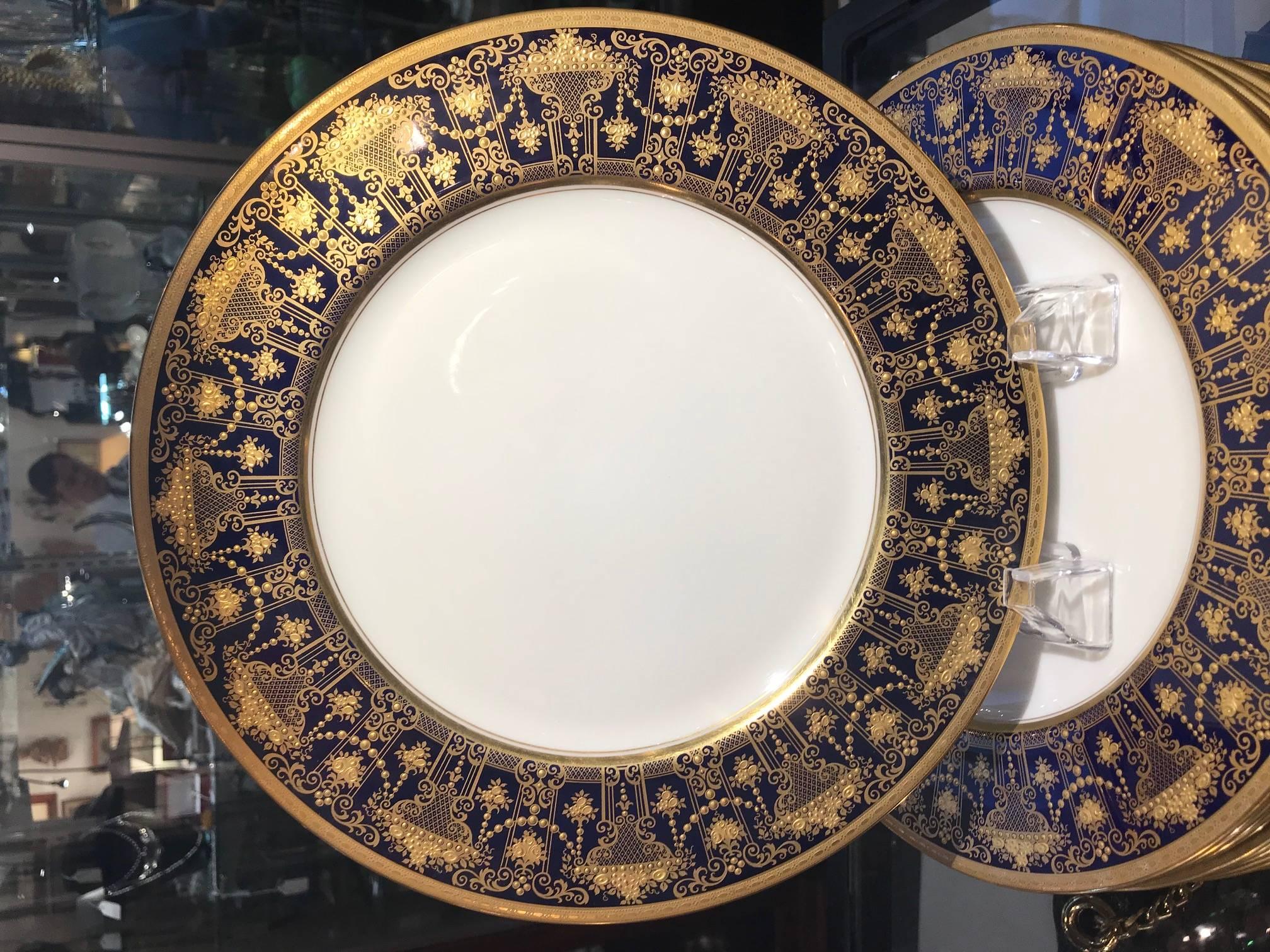 An exceptionally beautiful set of 12, circa 1910 Lenox green mark dinner plates feature a deep cobalt blue border and elaborate acid-etched gold borders. The lavish raised paste gold neoclassical garlands and arches make an elegant statement. These