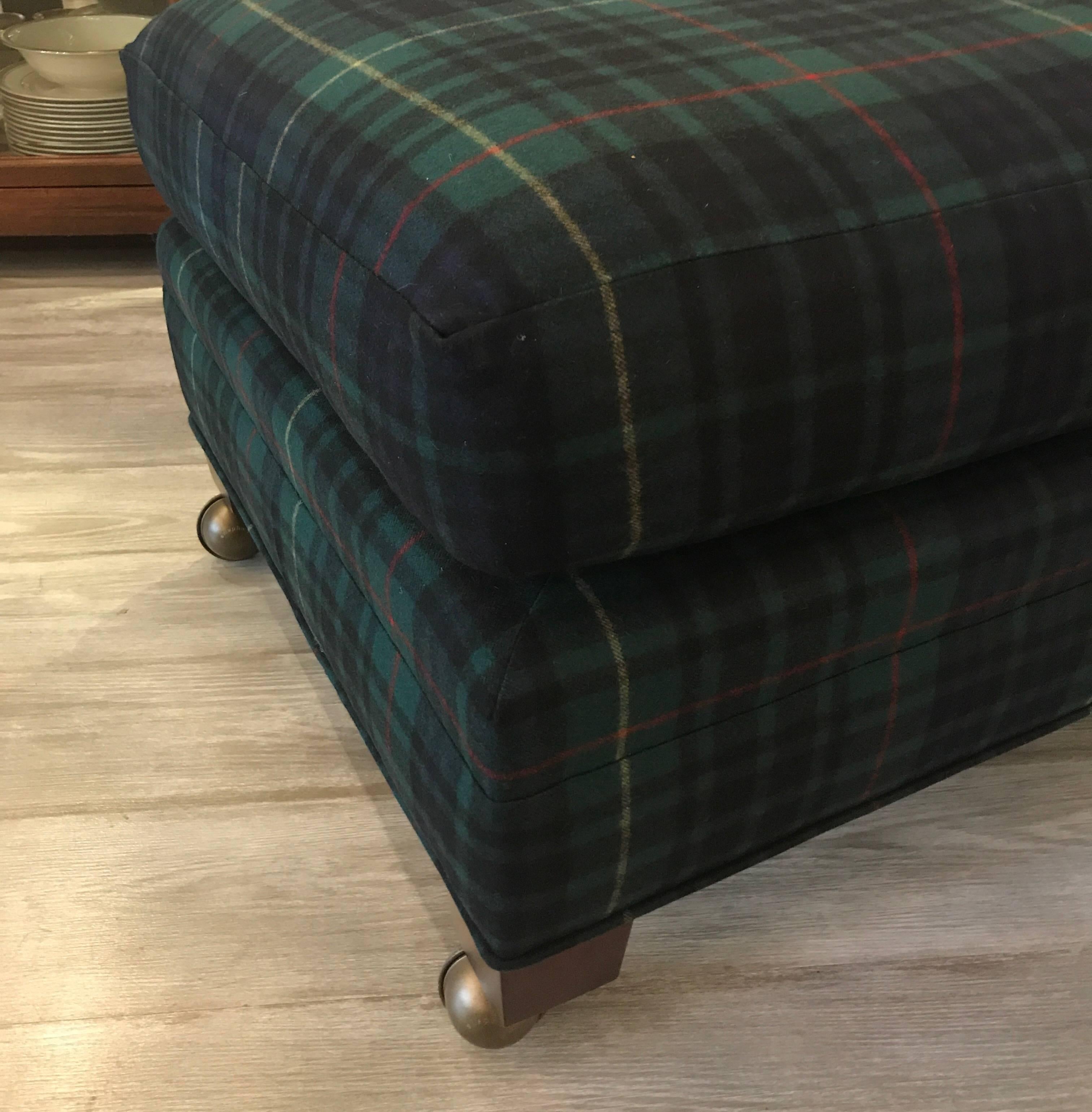 A large castored ottoman by Baker in new 100% wool Keighley tartan black fabric. The Ralph Lauren fabric was made in Italy. Luxurious and warm in deep shades of hunter and cobalt.