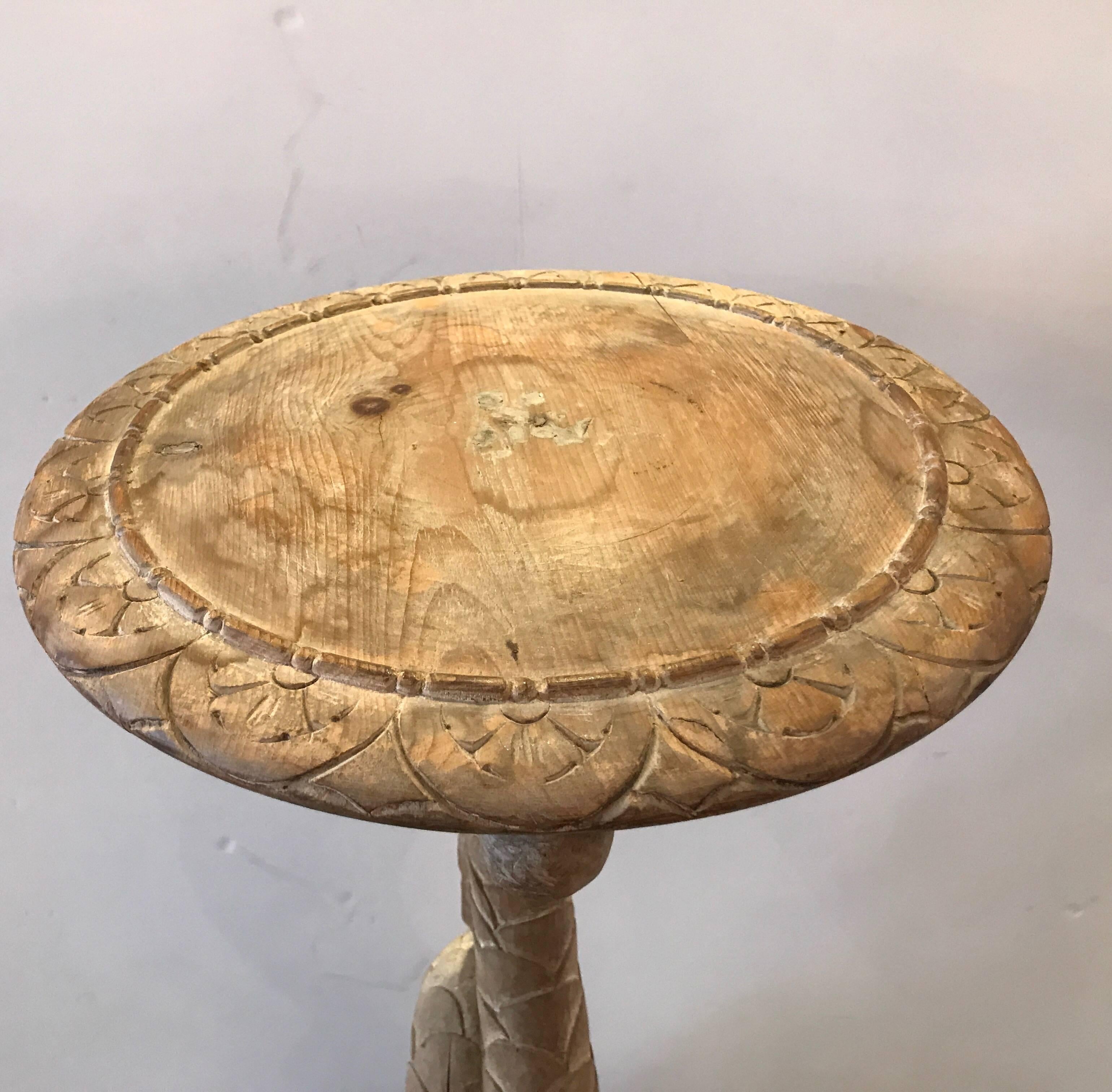 A pair of hand-carved hard pine dolphin motif pedestals. The round tops are 14.5 inches in diameter. The center columns are hand-carved in the form of dolphins. The finish is a scrubbed pine with traces of paint.