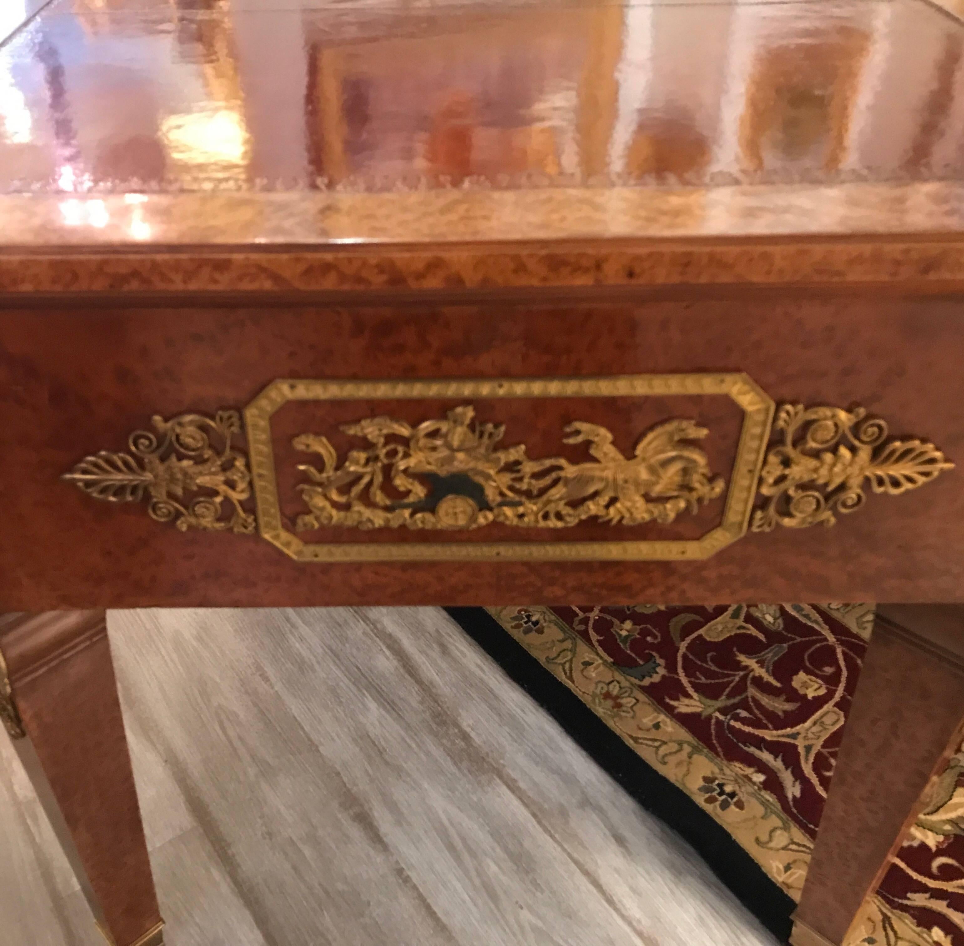 Handsome and large leather topped neoclassic desk with ormolu mounts. The front with three drawers with gilt bronze handles and mounts with a finished back. The leather top is an iron red with tooled gilt edge.