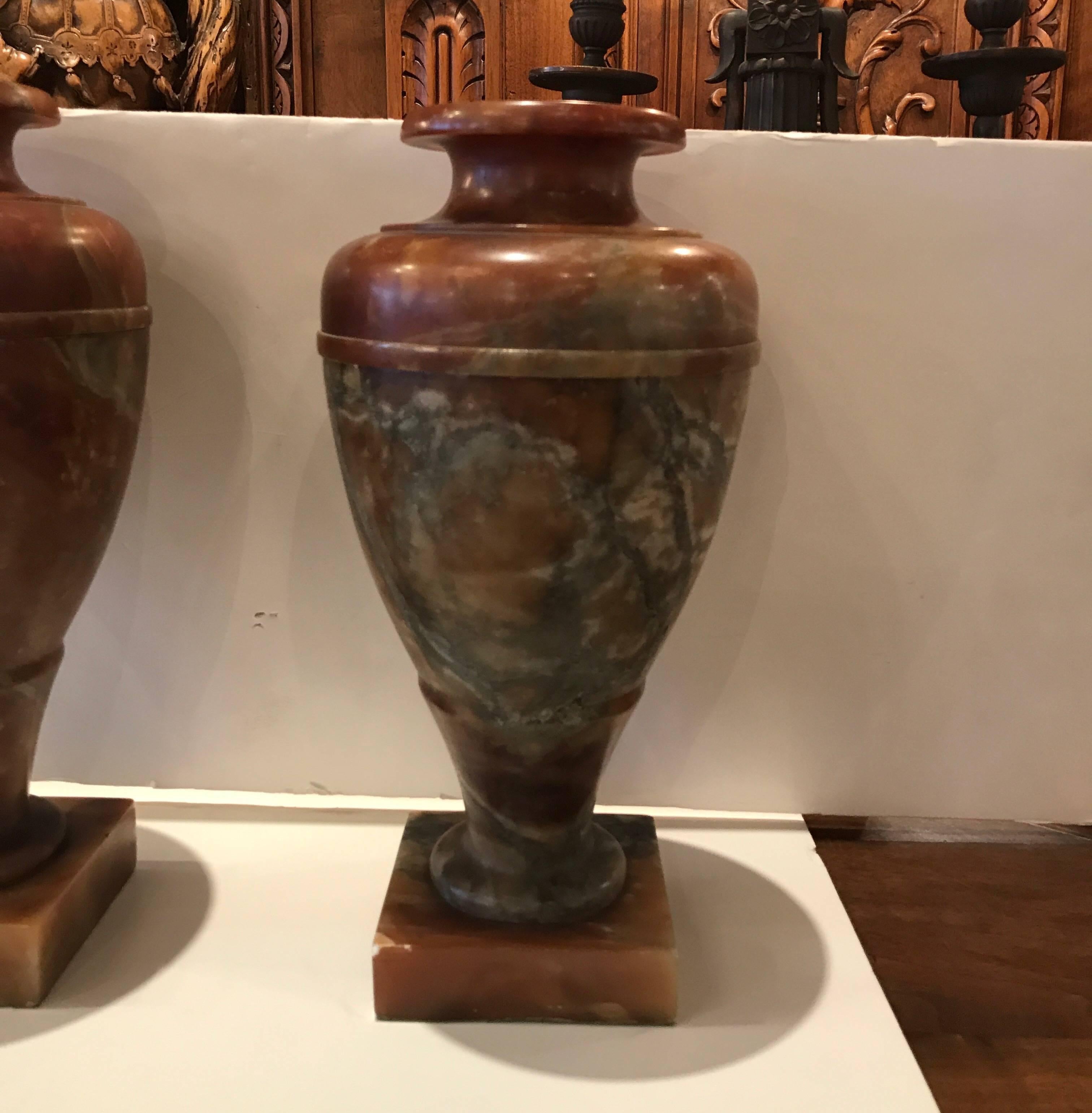 A pair of natural rouge marble urn luminary lamps. The marble in a deep amber color with natural veining in shades of grey. The lids lift to allow access to the bulbs. Each take a standard chandelier bulb, Italy, 1920s.