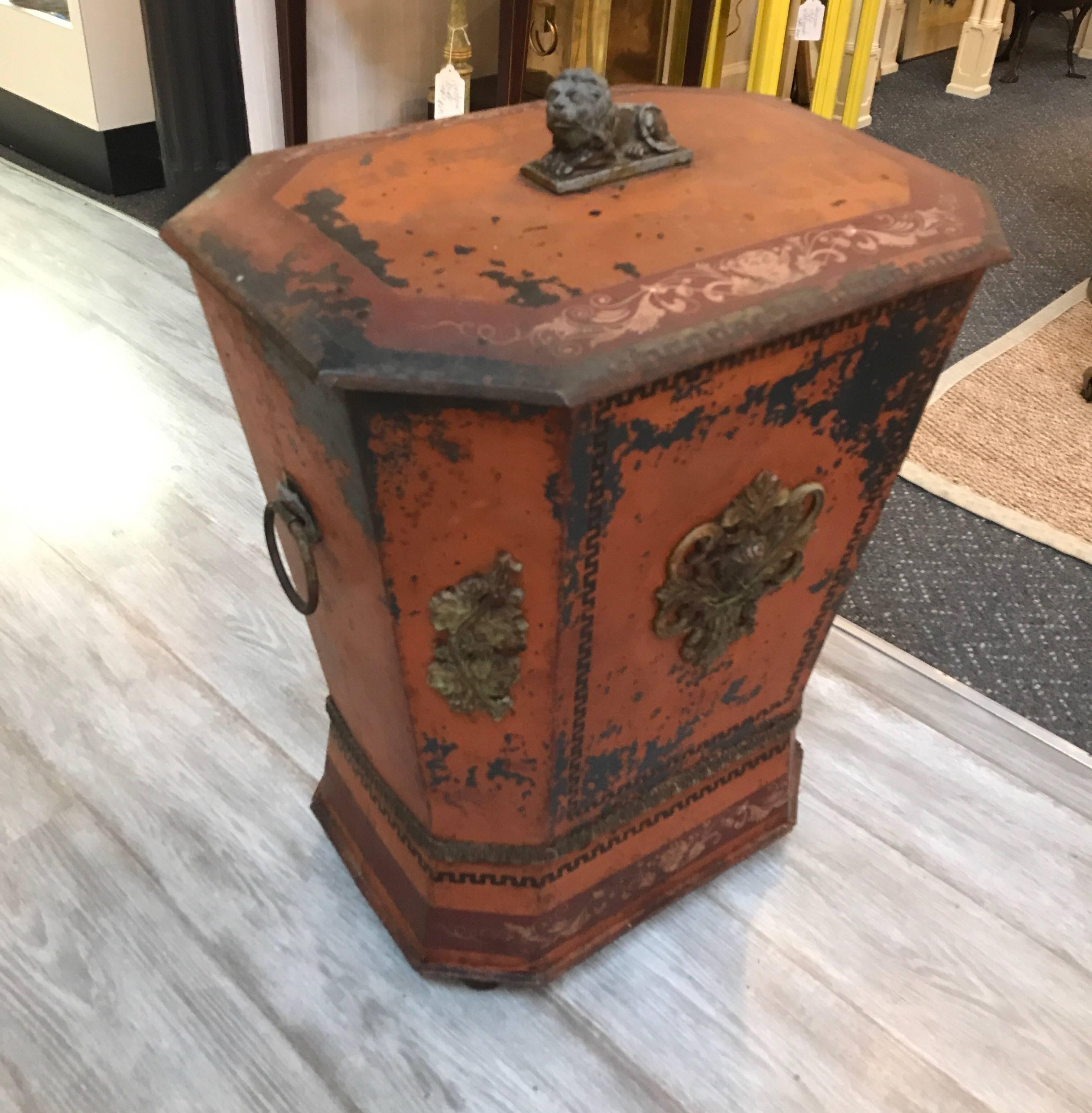 The tole tinder box with original paint showing years of well cared for use, the background color is a pumpkin orange with gilt and painted highlights with a zinc lion finial top and ring handles.