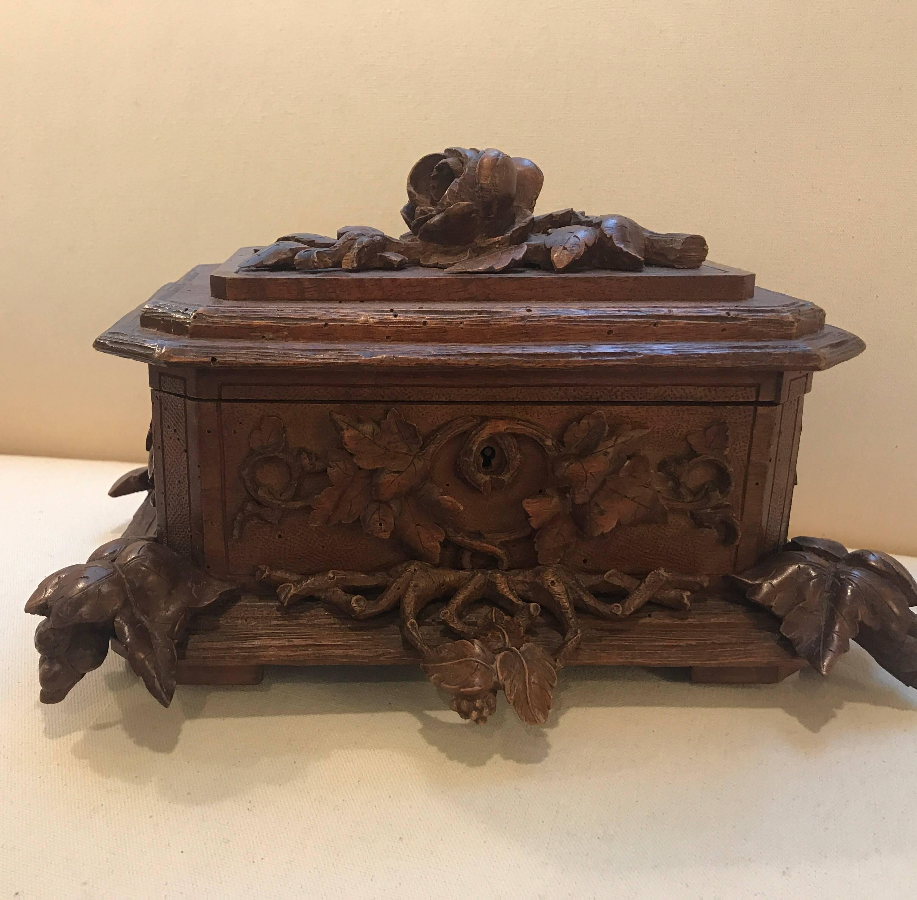 Expertly hand-carved Swiss black forest hand-carved table box. The hinged lid with floral and vine decoration over a carved bottom with ivy motif feet.