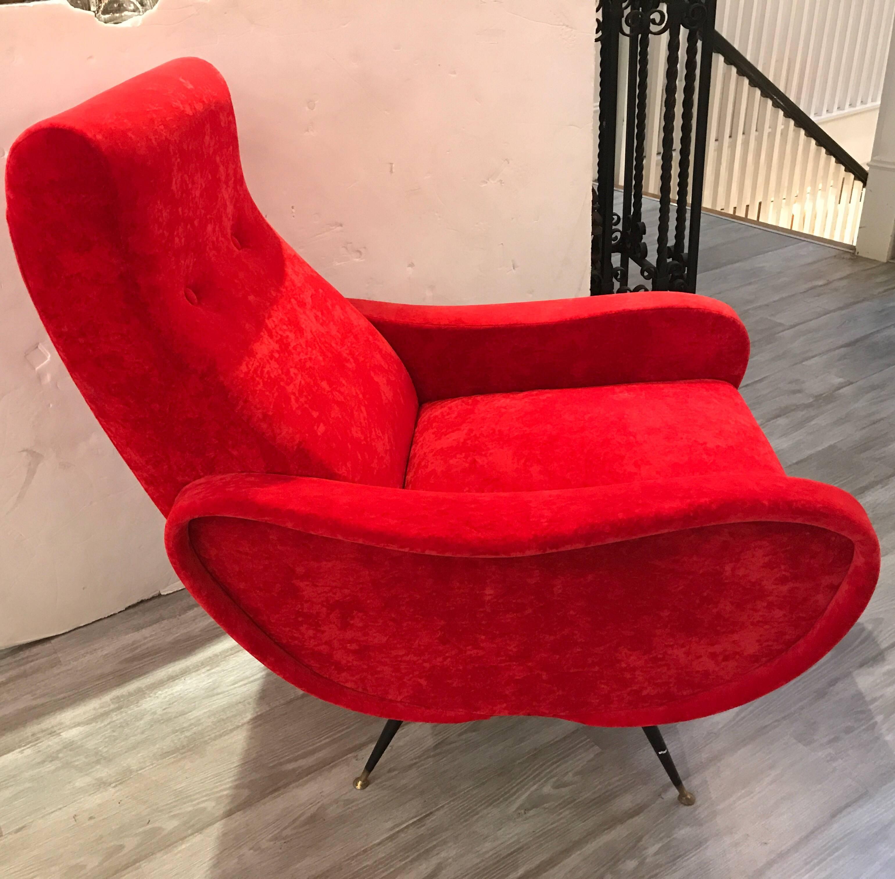 This beautiful sculpted pair of 1950s Italian modern armchairs feature tapered legs with brass tipped feet. The vibrant red velvet with two back buttons, the Silhouette is very curved and comfortable.