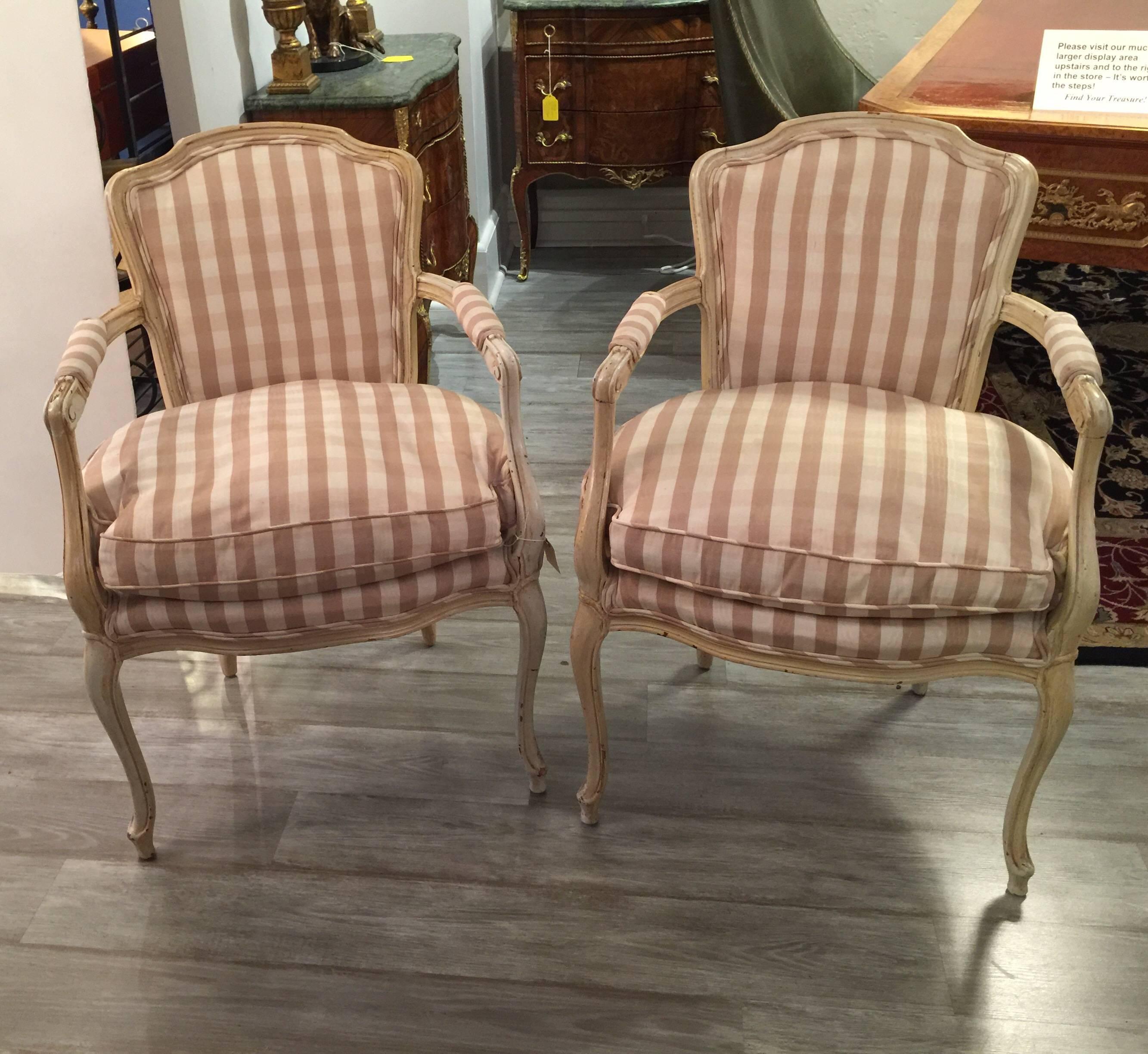 A graceful pair of cream distress painted Louis XV style armchairs with taffeta upholstery. The cream white frames with light distressing with cream and taupe plaid taffeta back and seats. The removable seat cushion with down and feather filling.