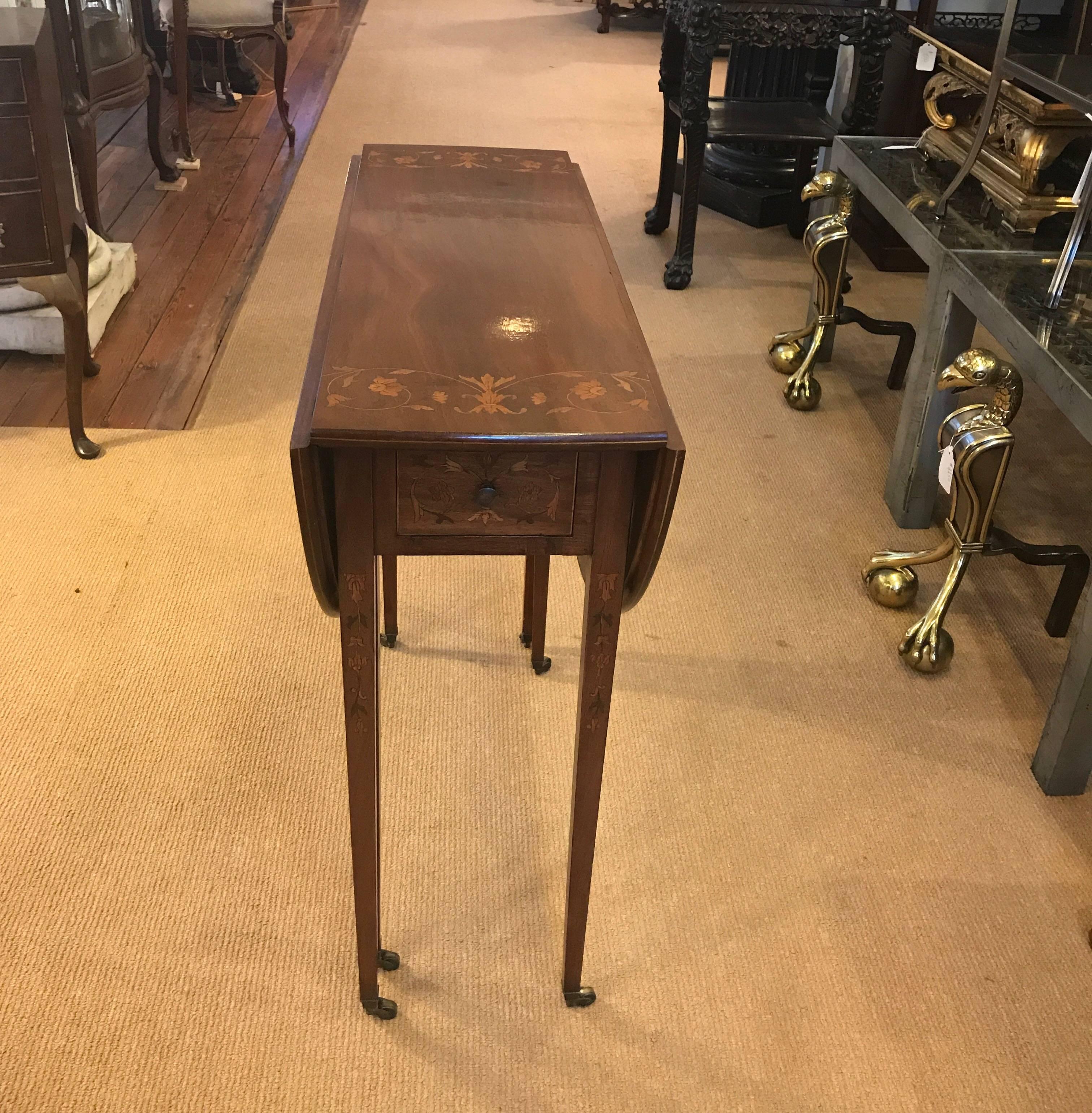 Beautiful tall and slim mahogany drop-leaf table. Larger than a Pembroke table but similarly styled. The 29 inch high table can be used as a ready when needed breakfast table. The all-over inlay along the top and leaf edges as well as on the legs