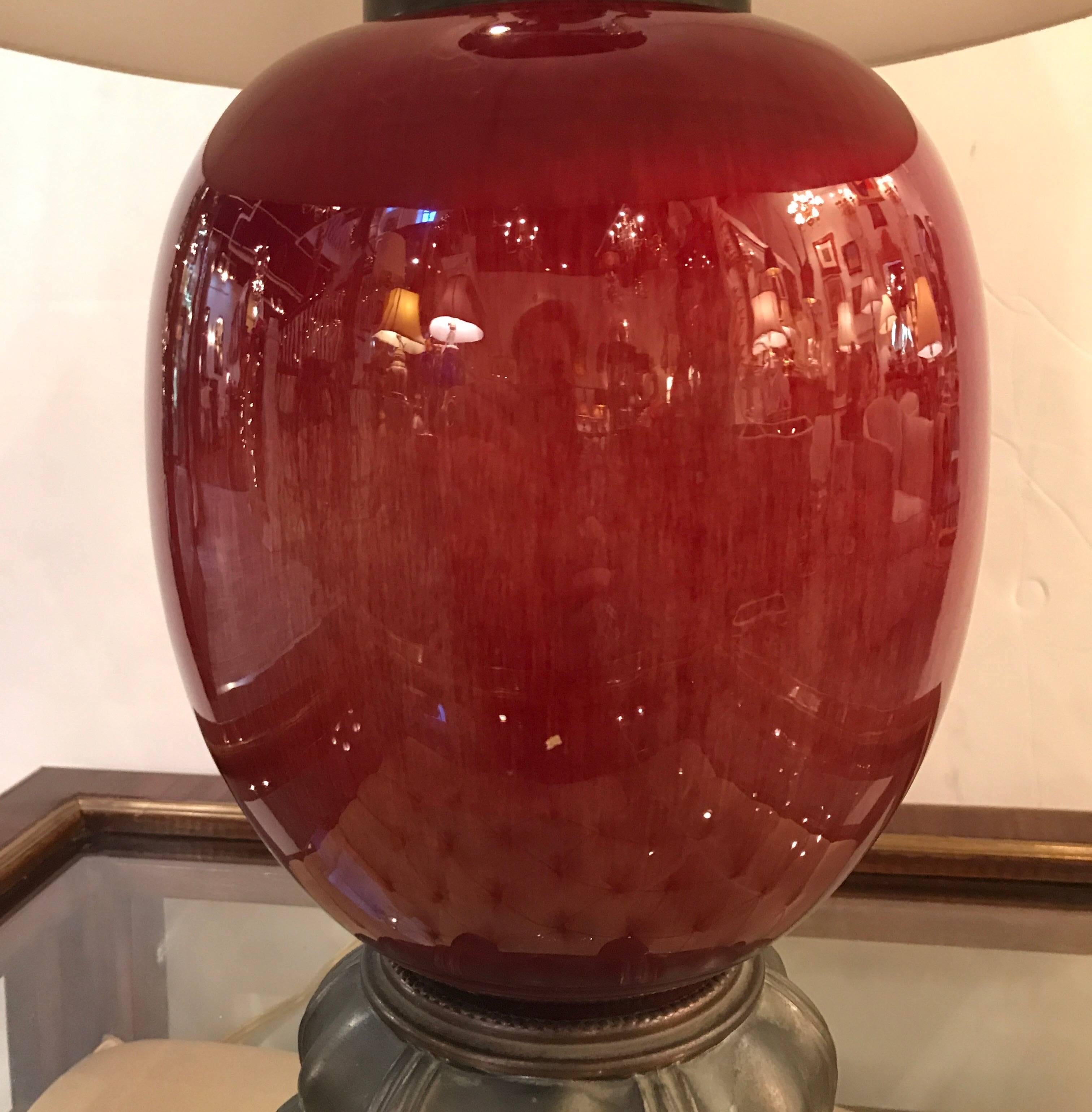 Lámpara Sang de Boeuf Art Déco de principios del siglo XX. El delicioso esmalte rojo flambeado con acabado en bronce se monta con cableado eléctrico nuevo y soportes con motivo de loto en acabado bronce. La pantalla simple es sólo para fines