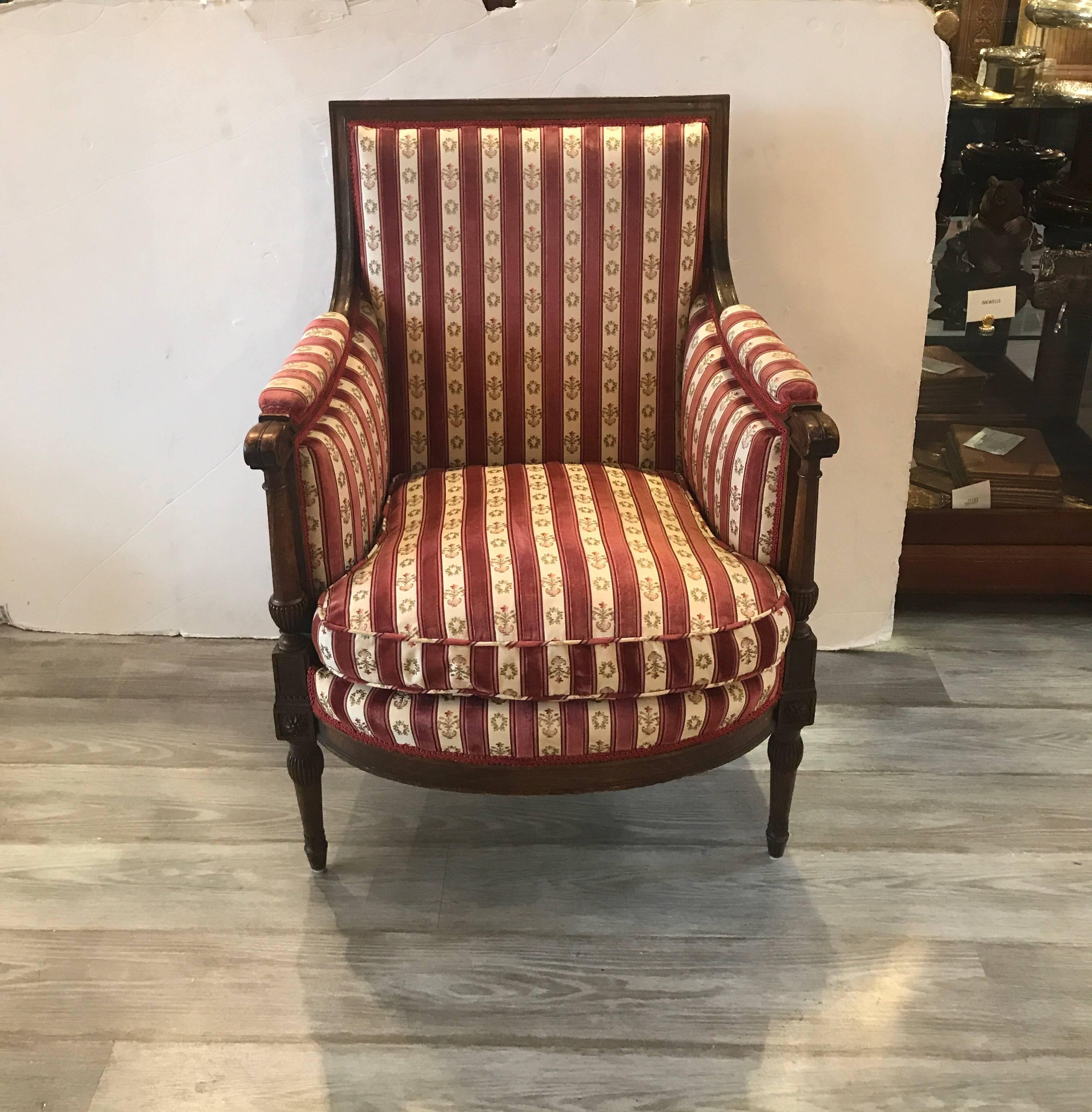Elegant hand-carved Louis XVI Style chair in walnut. The Classic style frame with carve detail on arms and legs, covered in a silk velvet and brocade stripe. The fabric is in excellent condition but can also be easily changed to suit the new
