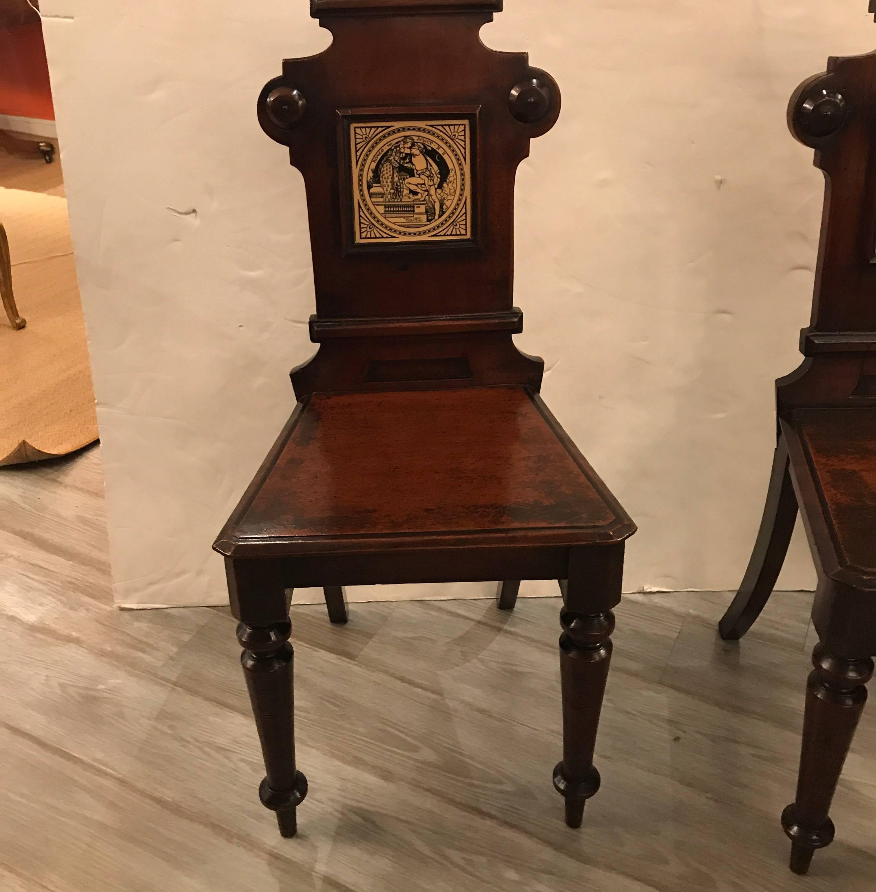 A Stately pair of mahogany hall chairs with Minton tiles set into the backs.  The solid mahogany with original well cared for finish. The tiles are scenes from Shakespeares Romeo and Juliet.  
