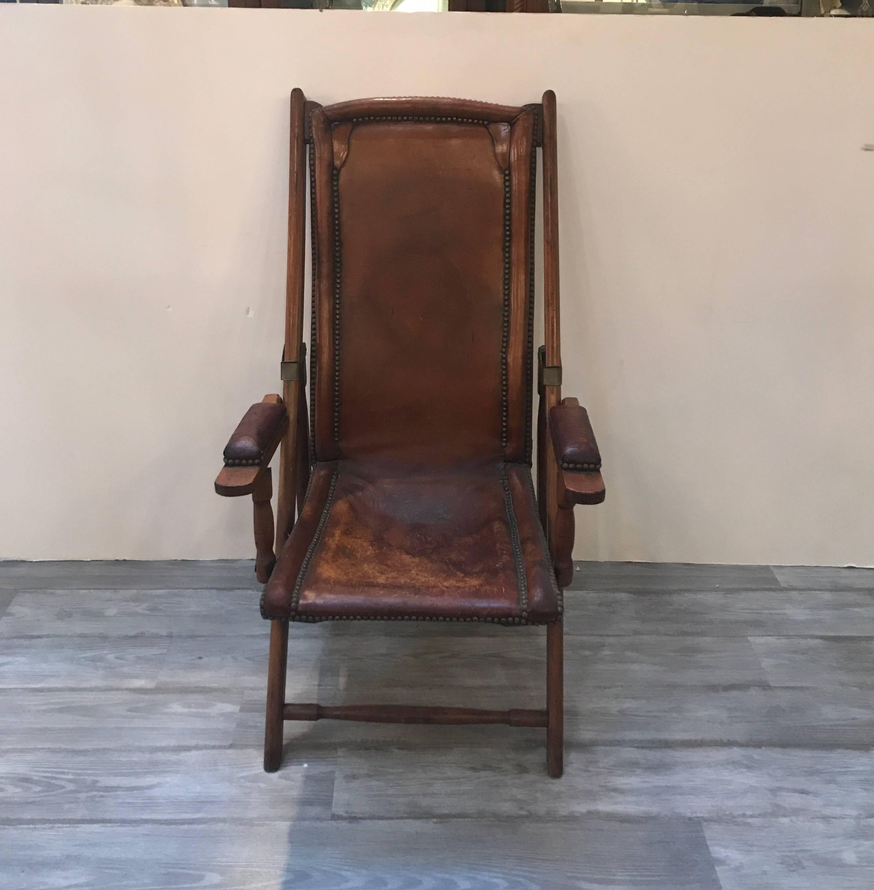 Very rare antique English campaign chair. The leather seat and back with original brass nail head trim. The medium tone mahogany frame with leather padded arm rests. The original leather is distressed like a saddle.