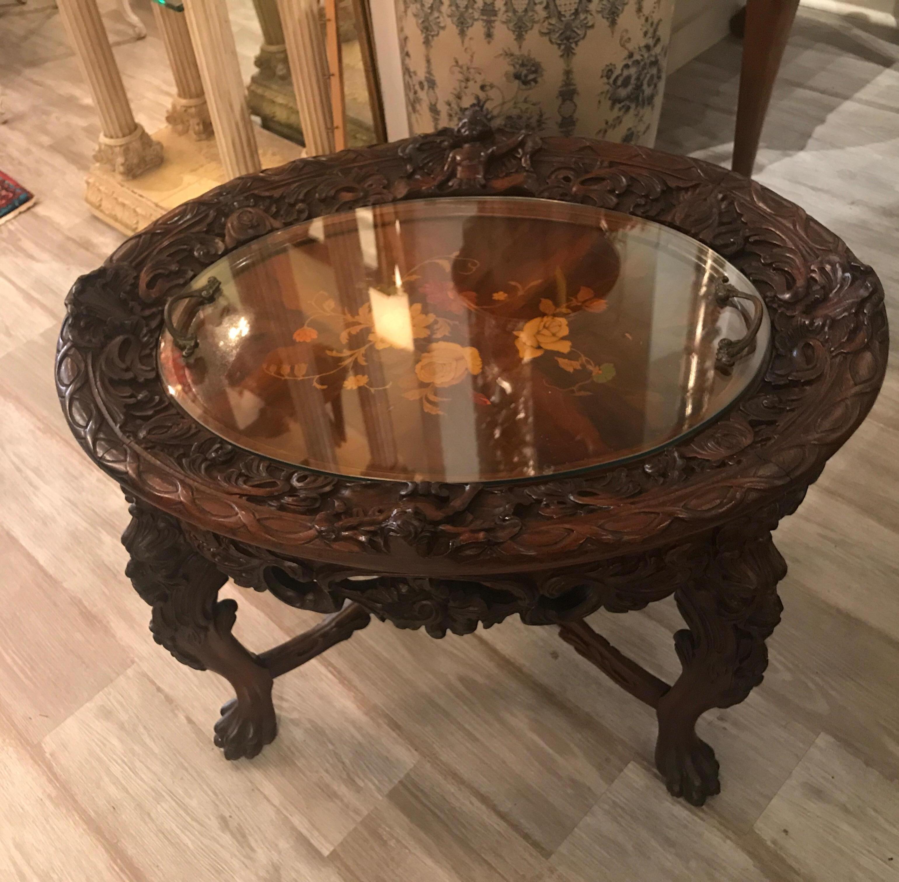 Heavily carved walnut table with inlaid top. The top with oval fitted glass tray with case brass handles. Nice smaller size.