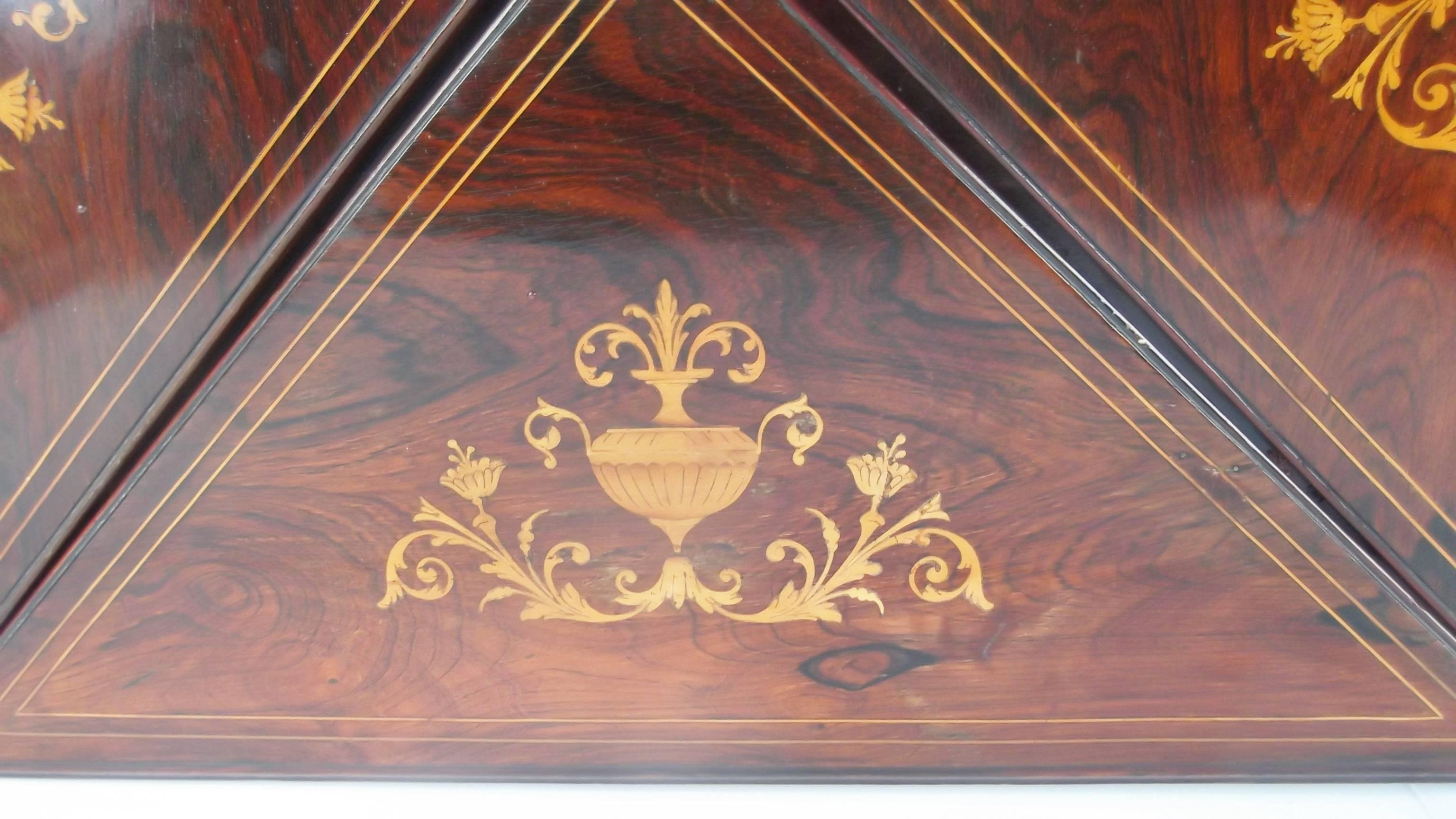 Beautiful English rosewood game table with satinwood hand inlaid decoration..  The handkerchief triangular leaves flip open to reveal the leather topped gaming surface.  Intricate and exceptional inlay on the top and front legs.  The lower shelf is