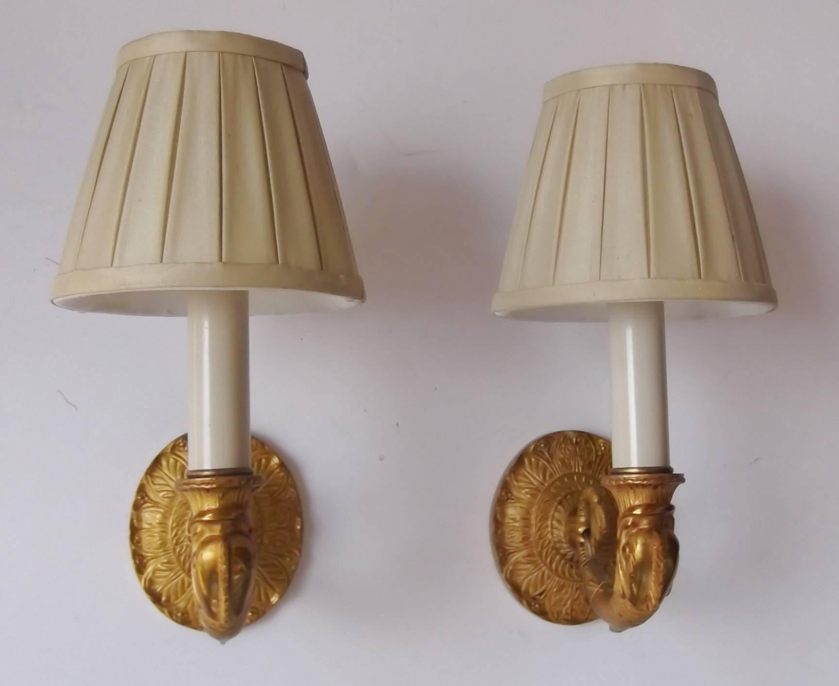 French Cast gilt bronze single light sconces.  Classic empire styling with a dolphin shaped arm supported by an oval back plate.  Recently rewired and ready to light.  These are the old style 