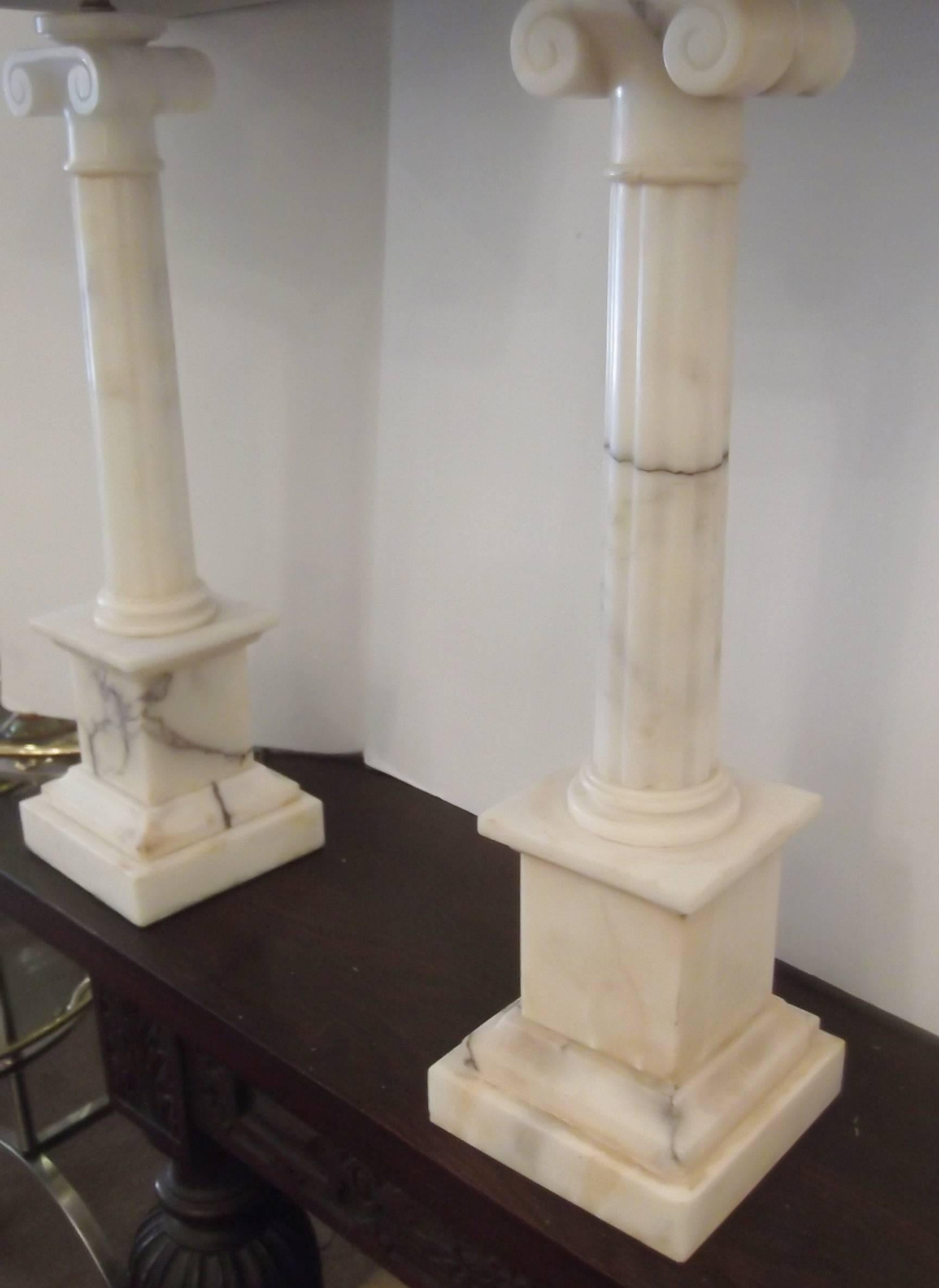 A handsome pair of Italian marble column lamps.
Classic Ionic capitol topped columns with fluted center columns on plinth bases. These are a solid marble with the grey veining. Paired with a simple black shade this look appropriate in any style