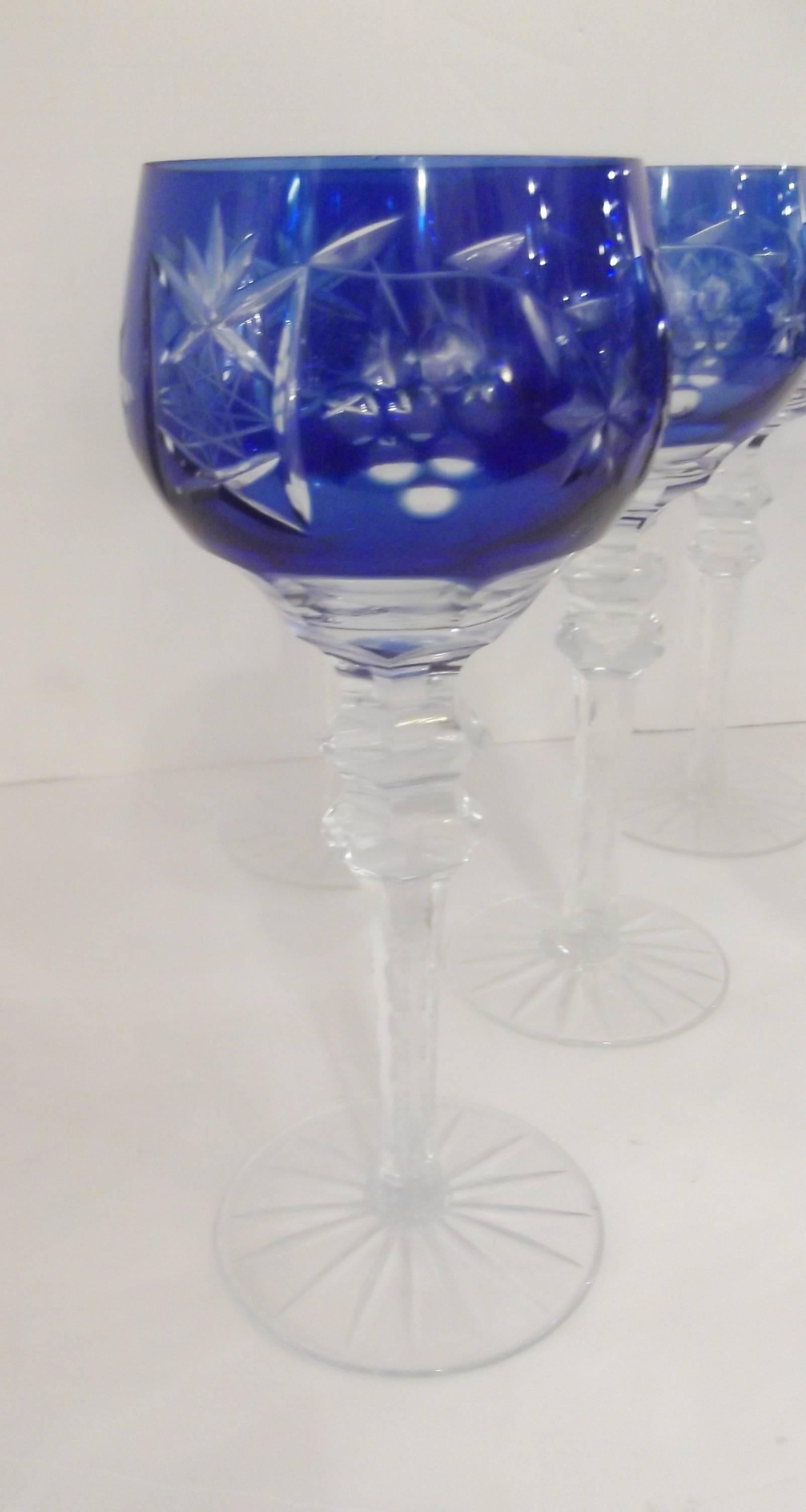 A Set of eight beautifully cut wine glasses.  Cobalt encased glass cut in a grape patter to reveal the clear glass.  The stems are faceted under the bowls with notched stems and starburst bottom.  All hand cut.