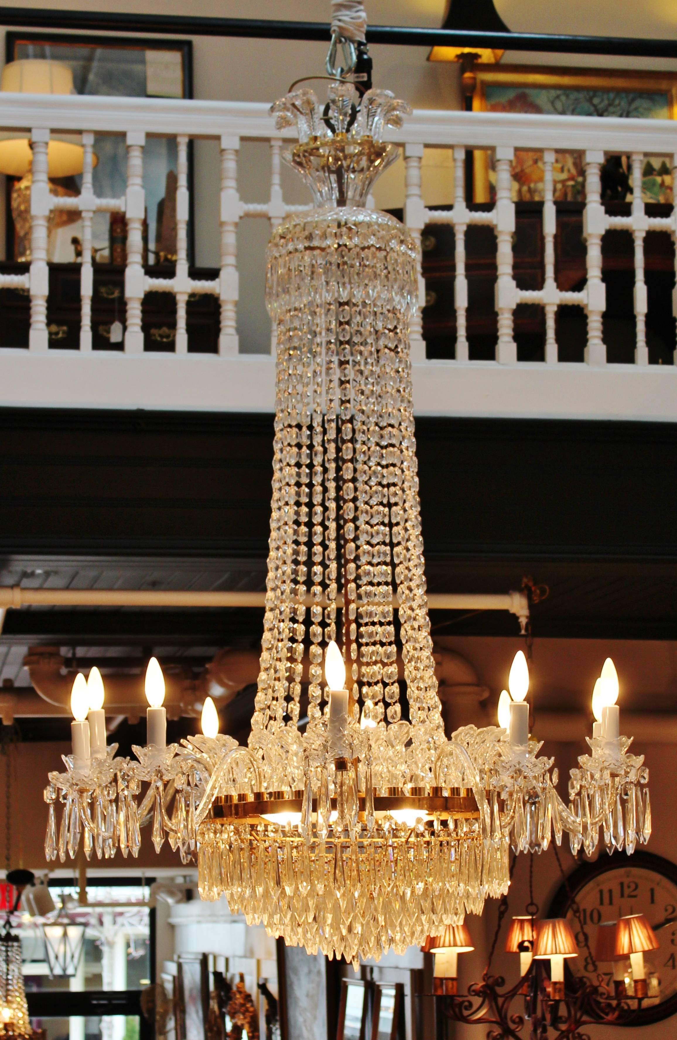 A Large Waterford grand ten-arm chandelier. Ten lights with five more interior lights with cut plume top crown underneath strands of faceted beads. The bottom is layered rows of speared prisms. This custom-made size of 65 inches long and 45 inches