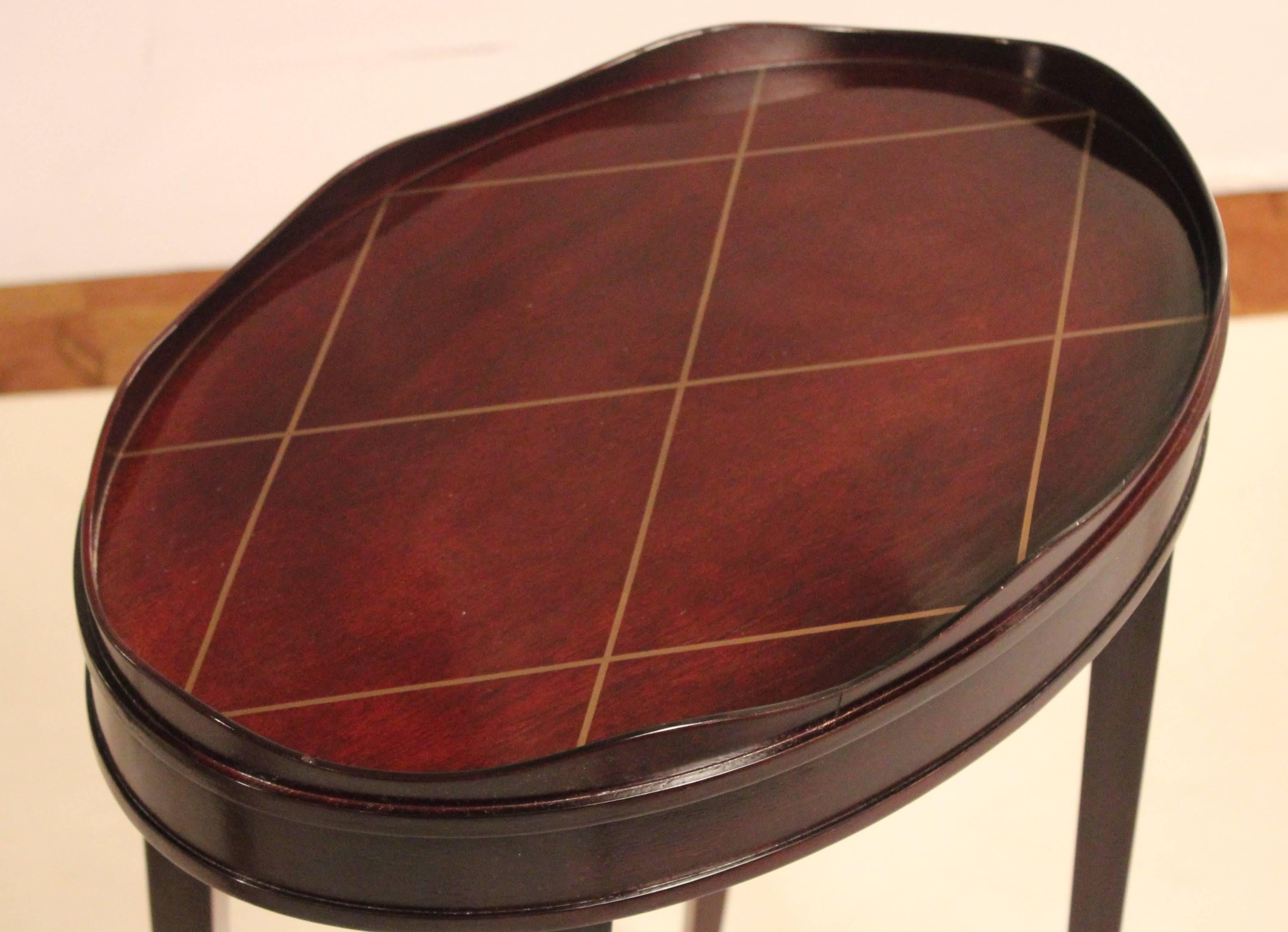 Mahogany oval accent table with gallery edge designed by Barbara Barry and made by the Baker Furniture company. Dark finish with muted gold lattice painted top. The four gently splayed legs end in an arrow style tip. This piece is best described as