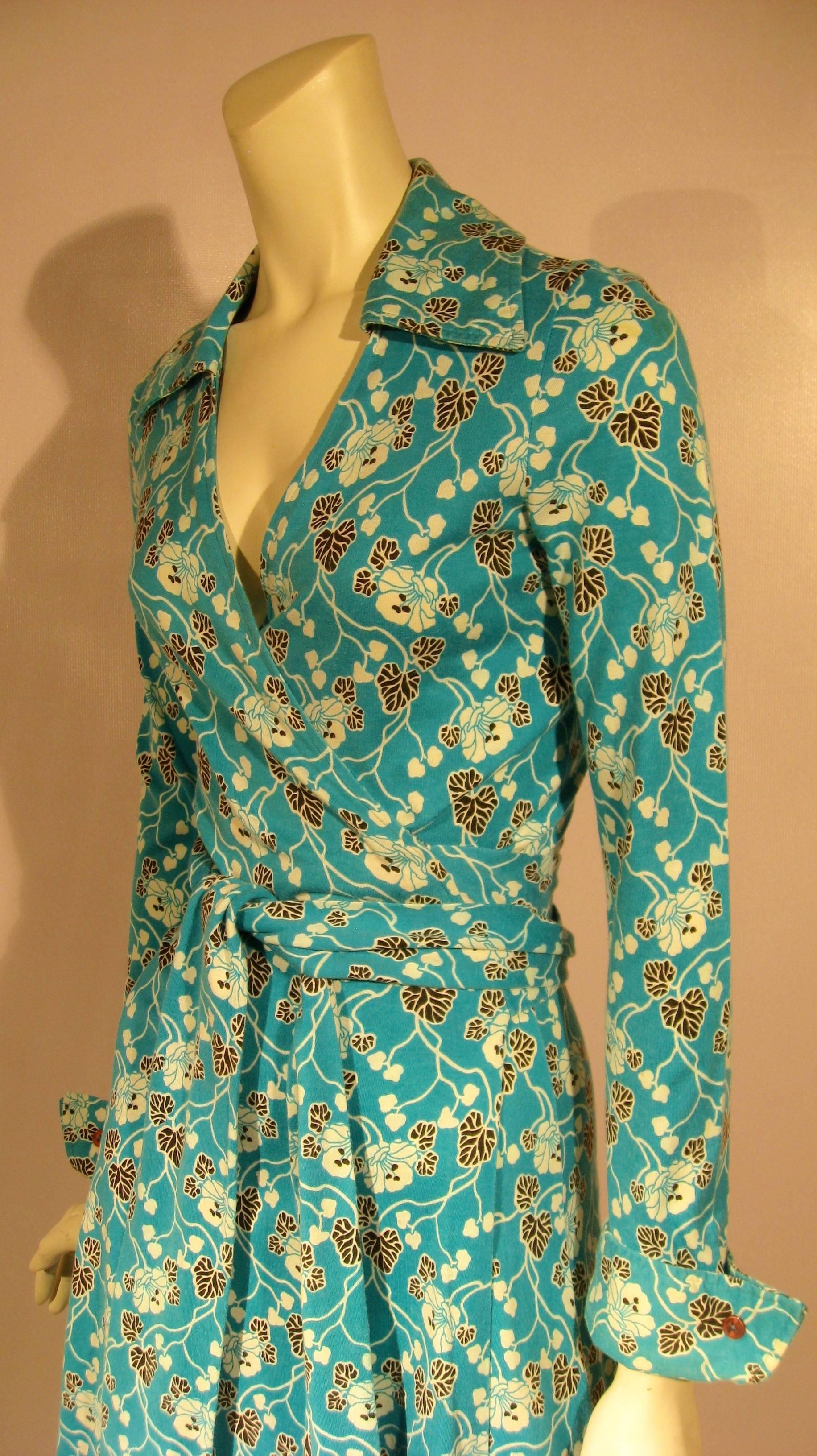 The most iconic Diane von Furstenberg design is her cotton/rayon wrap dress of the 1970s. This one is in a saturated turquoise with a floral, leaf and vine print in white and black. With the slightly elongated collar, French cuffs and waist tie that