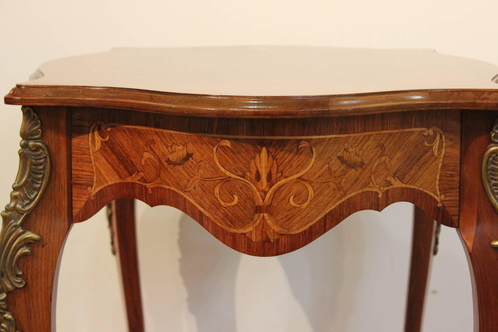 Beautiful inlaid occasional table with cast brass mounts. Shapely apron with delicate satinwood inlay, repeated on the top. The gently curved legs have cast brass mounts at the knees.