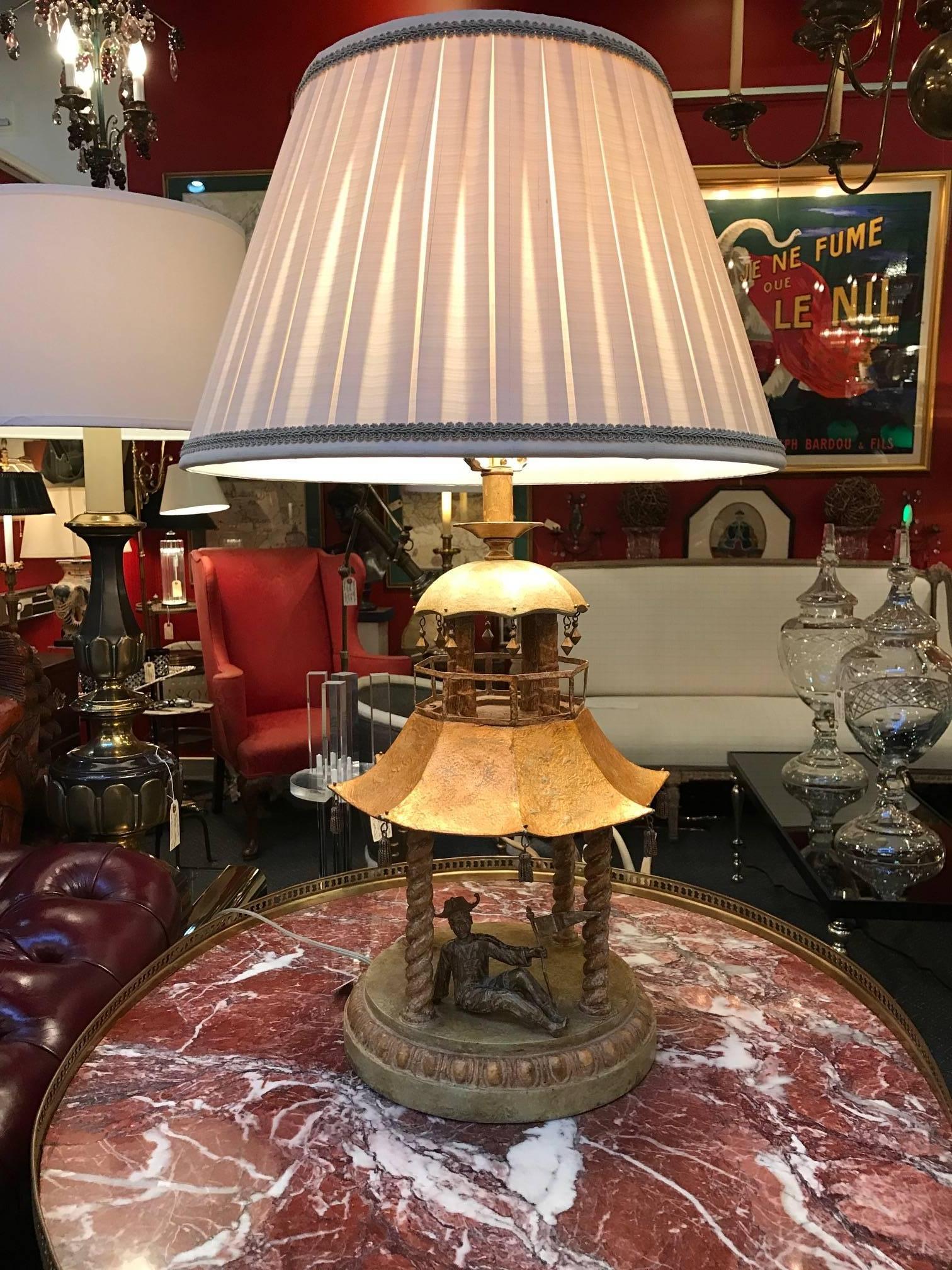 A gilt Asian inspired Pagoda lamp with custom silk pleated shade. The circular base with four columns supporting the Pagoda roof. The corners have a little bell shaped tassels on each tier. The shade has a built in silk light filter to soften the