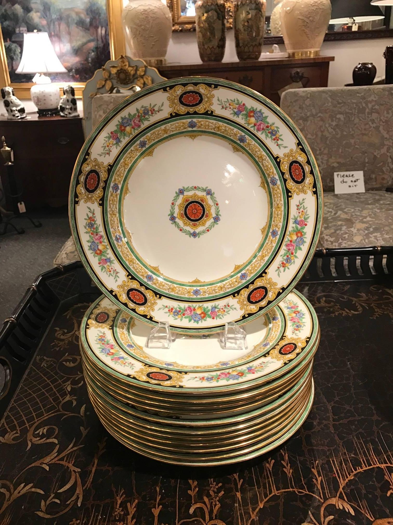 Elegant set of 12 hand-painted English dinner service plates. The hand enameled borders and centers with floral panels and lacy borders accented with ebony banding. Hand applied gilt edges.