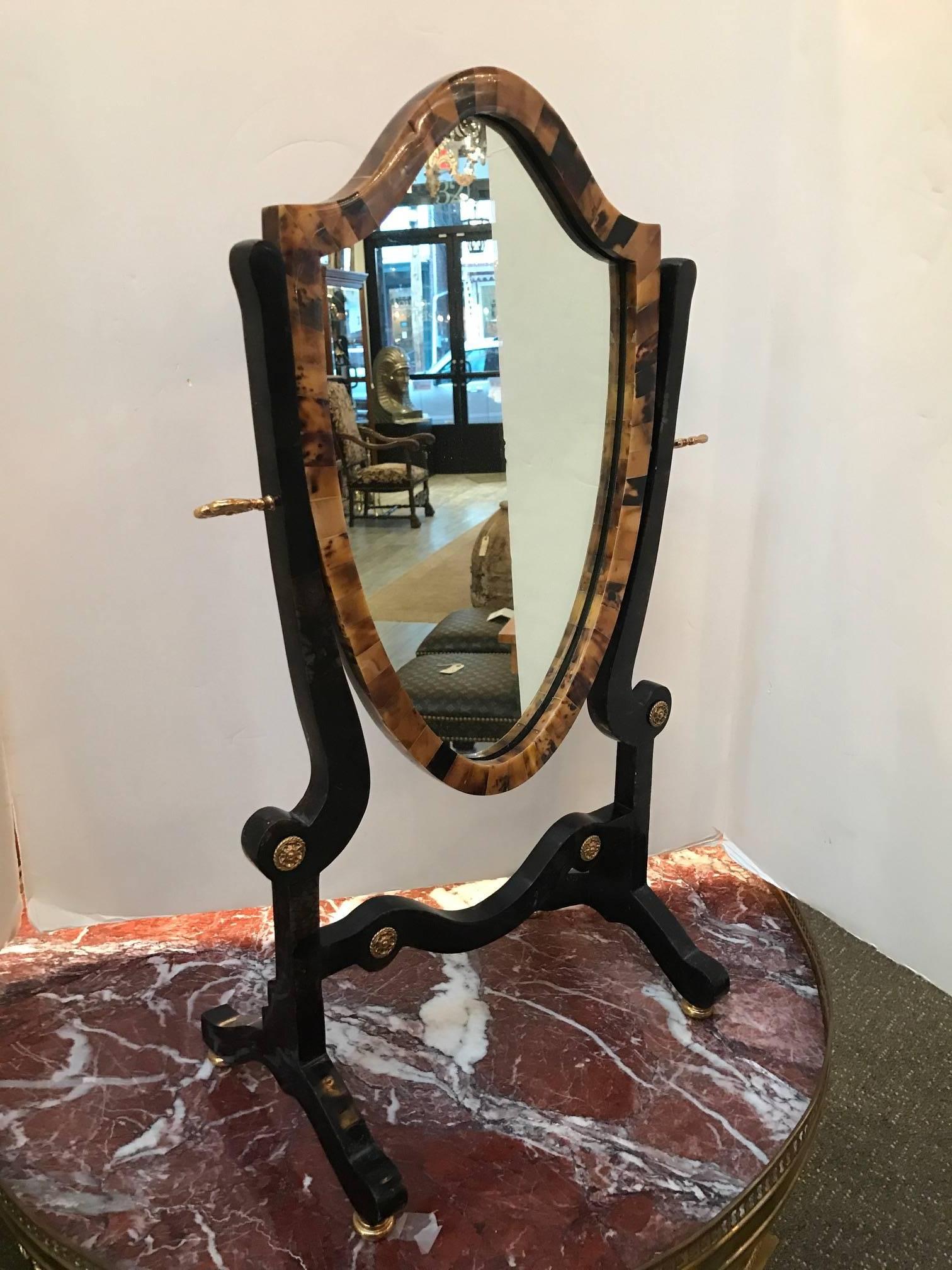 A tessellated stone and bronze-mounted standing vanity mirror. The Classic Hepplewhite style with a modern tessellated stone surface. The mirror is framed with a lighter stone in a tortoise shell color; the frame is a dark, almost black stone with