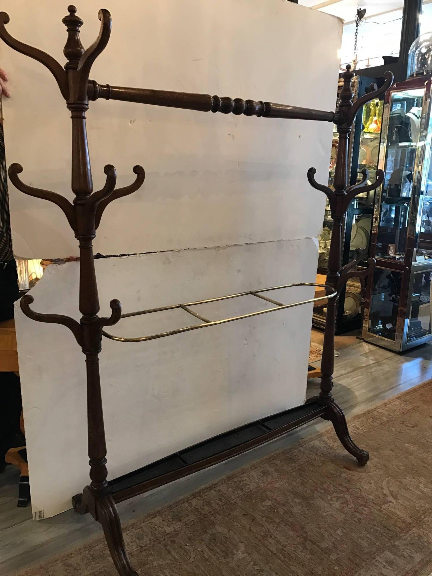 Unusual form double hall tree in the English Regency style, Late 19th century turned oak baluster ends with three tiers of hooks for hats and coats and a brass ring to hold canes and umbrellas with original tin tray at the base. The hall tree rests