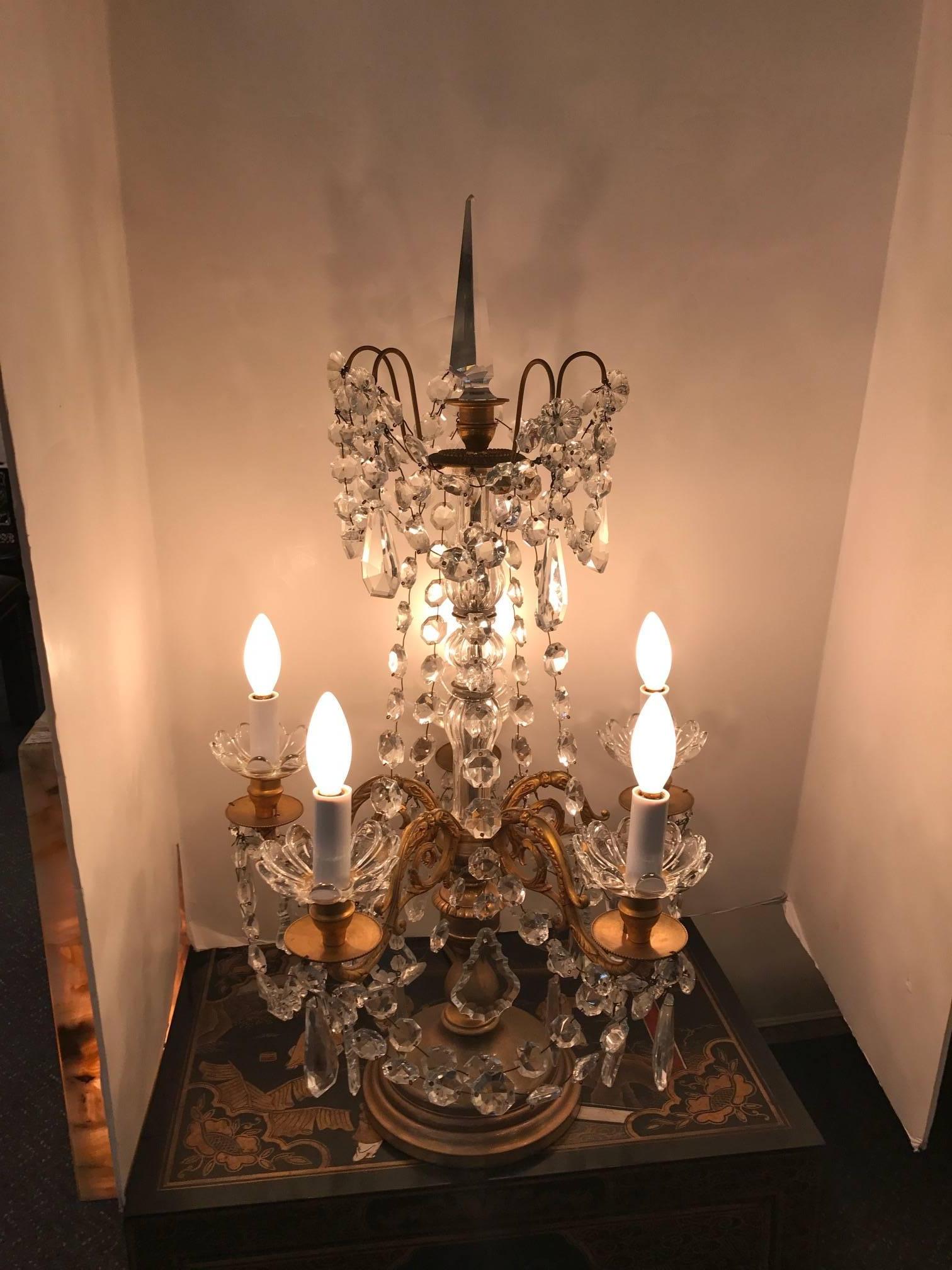 Elegant pair of French gilt bronze and crystal five-light girandole lamps. The top cut and polished spire supported by a molded glass and metal center column with five scrolling arms layered in draped cut-glass beading. On-off switch on cord.