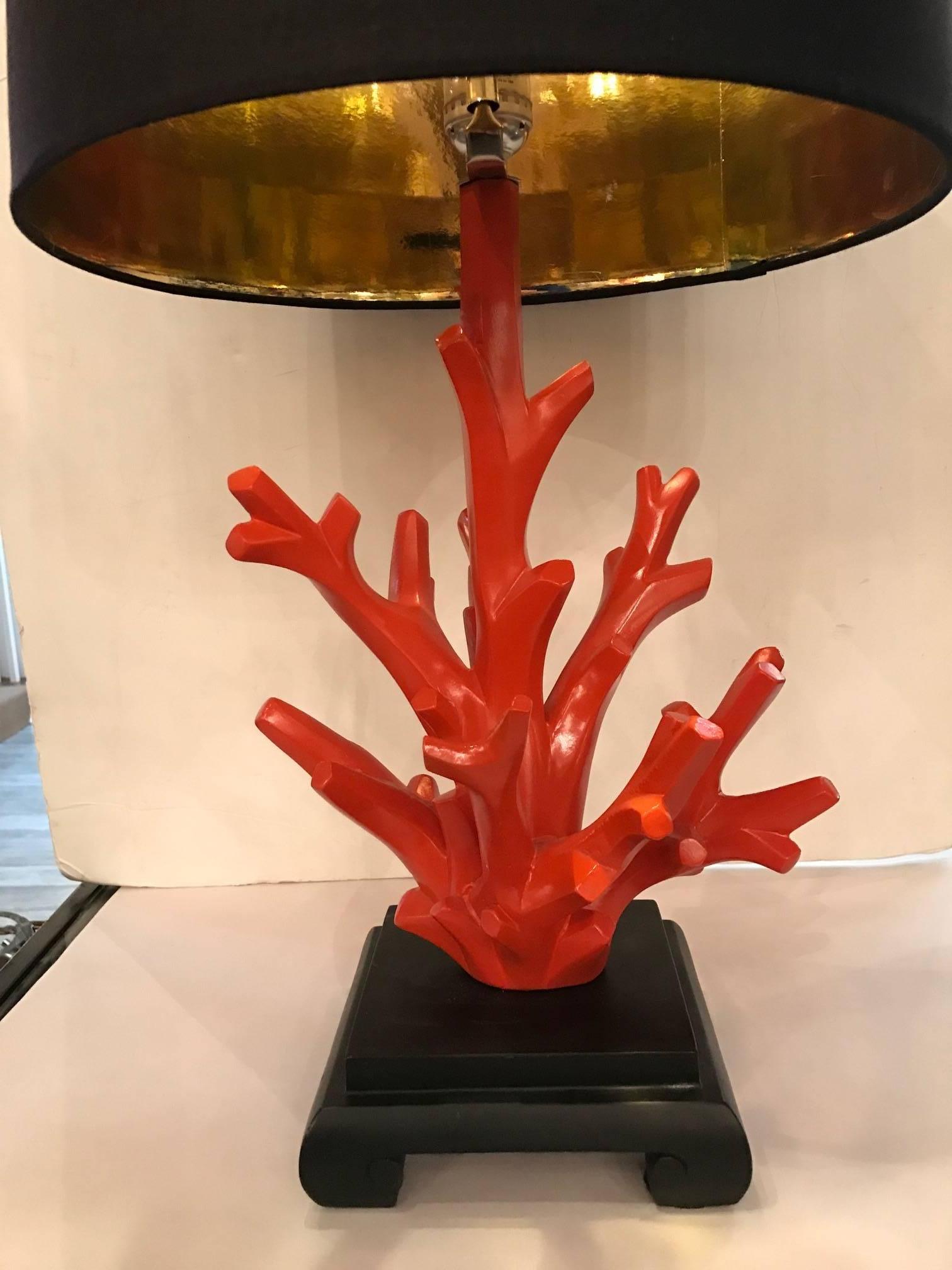 The lacquered orange red on a black Asian Style base topped with black foil lined shades. The finial is a match to the coral bodies. The bases measure 7 inches square.
