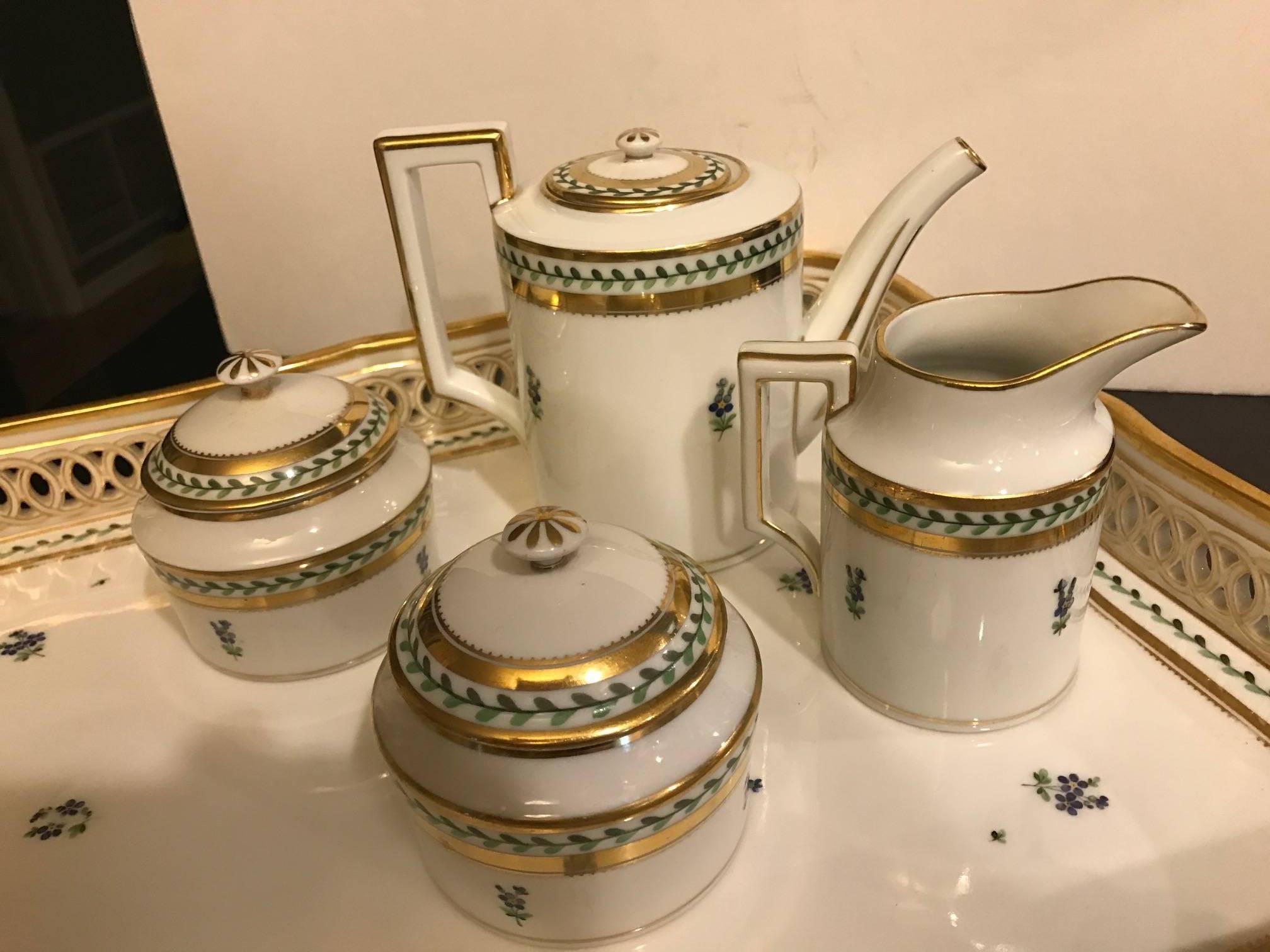 Extensive set of Wien Austrain porcelain tea set by Ernst Wahliss. Delicate hand gilt and painted with small coffee-tea pot, creamer, two lidded sugar bowls, eight smaller cups and saucers and two large cups and saucers with 12 cake plates. The set