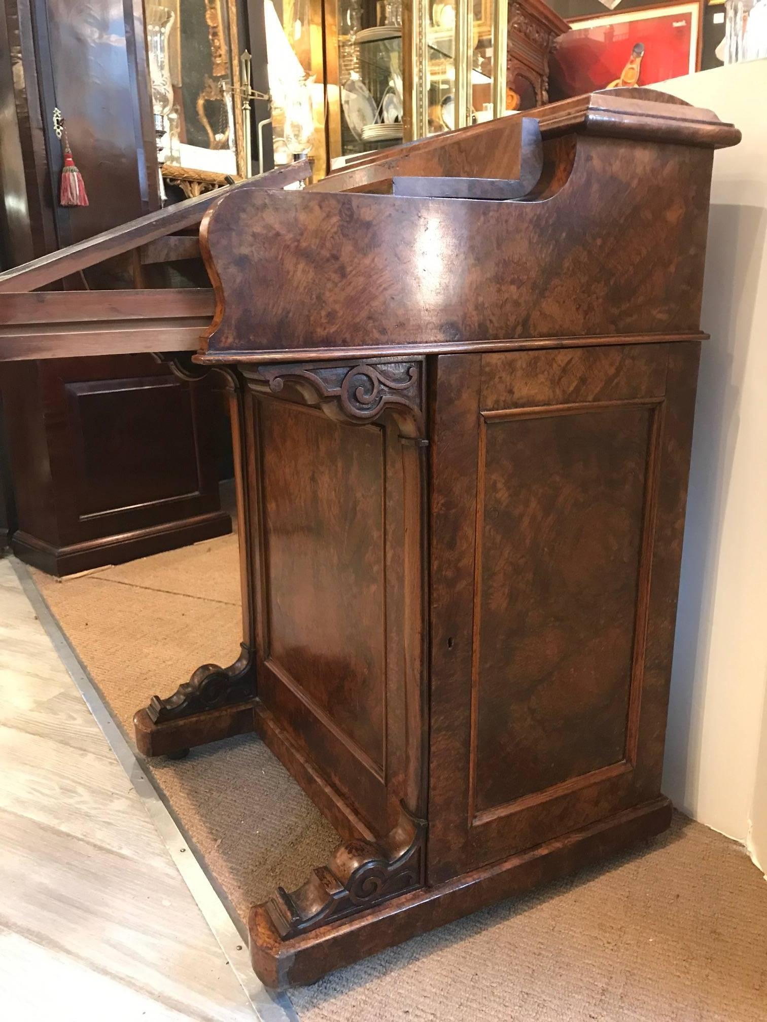 English burled walnut Davenport desk, circa 1840. The fold over top opening to reveal a pull-out writing surface, the right drawer hiding the catch that releases the mechanical pop up letter holder. The right side with a paneled door opens to