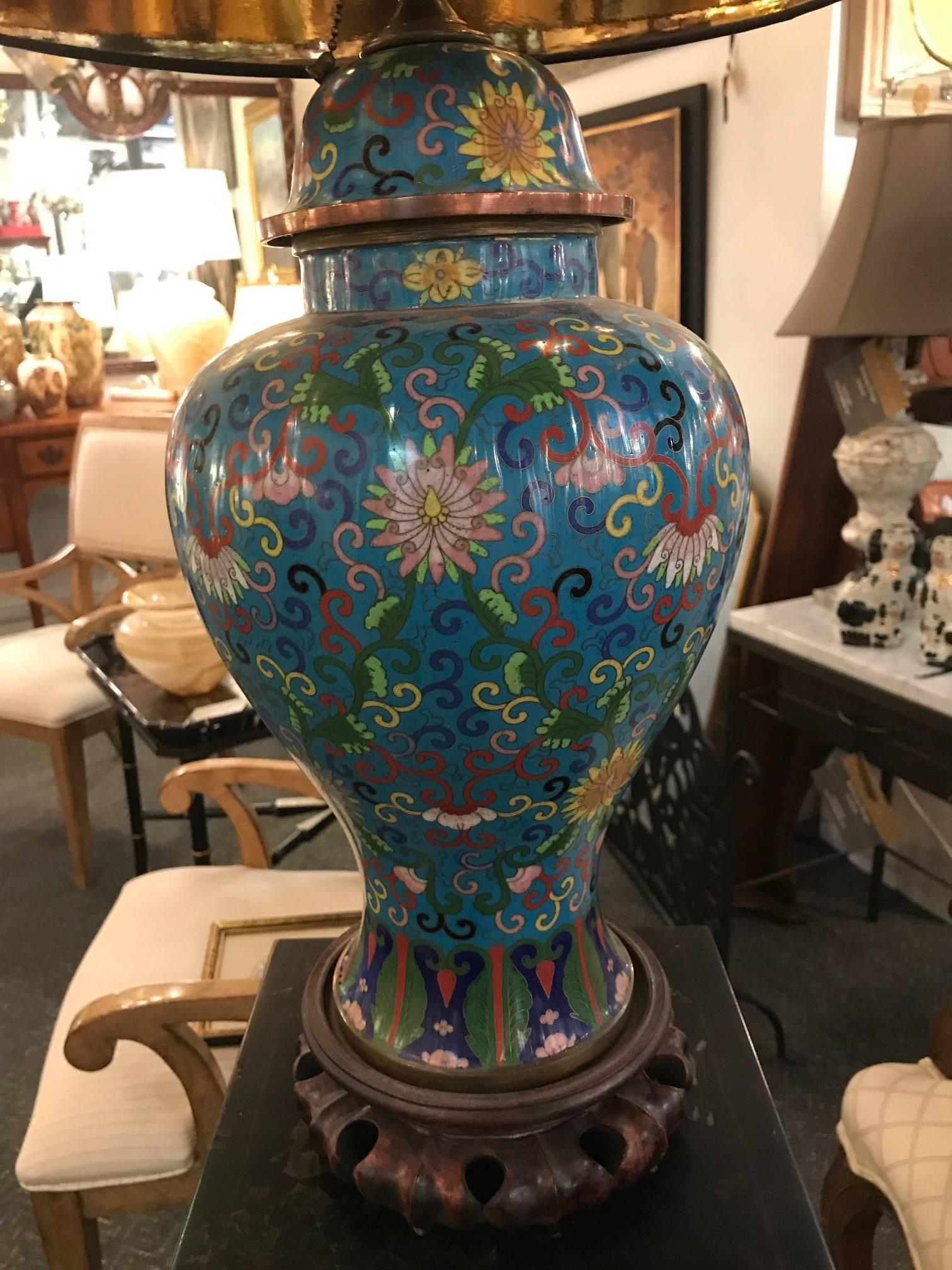Late 19th century Chinese cloisonne covered urn now as a lamp. Celeste blue background with intricate scrolling and floral decoration all-over. The hand-carved rosewood base is from the same period. The shade is for photographic purposes only and