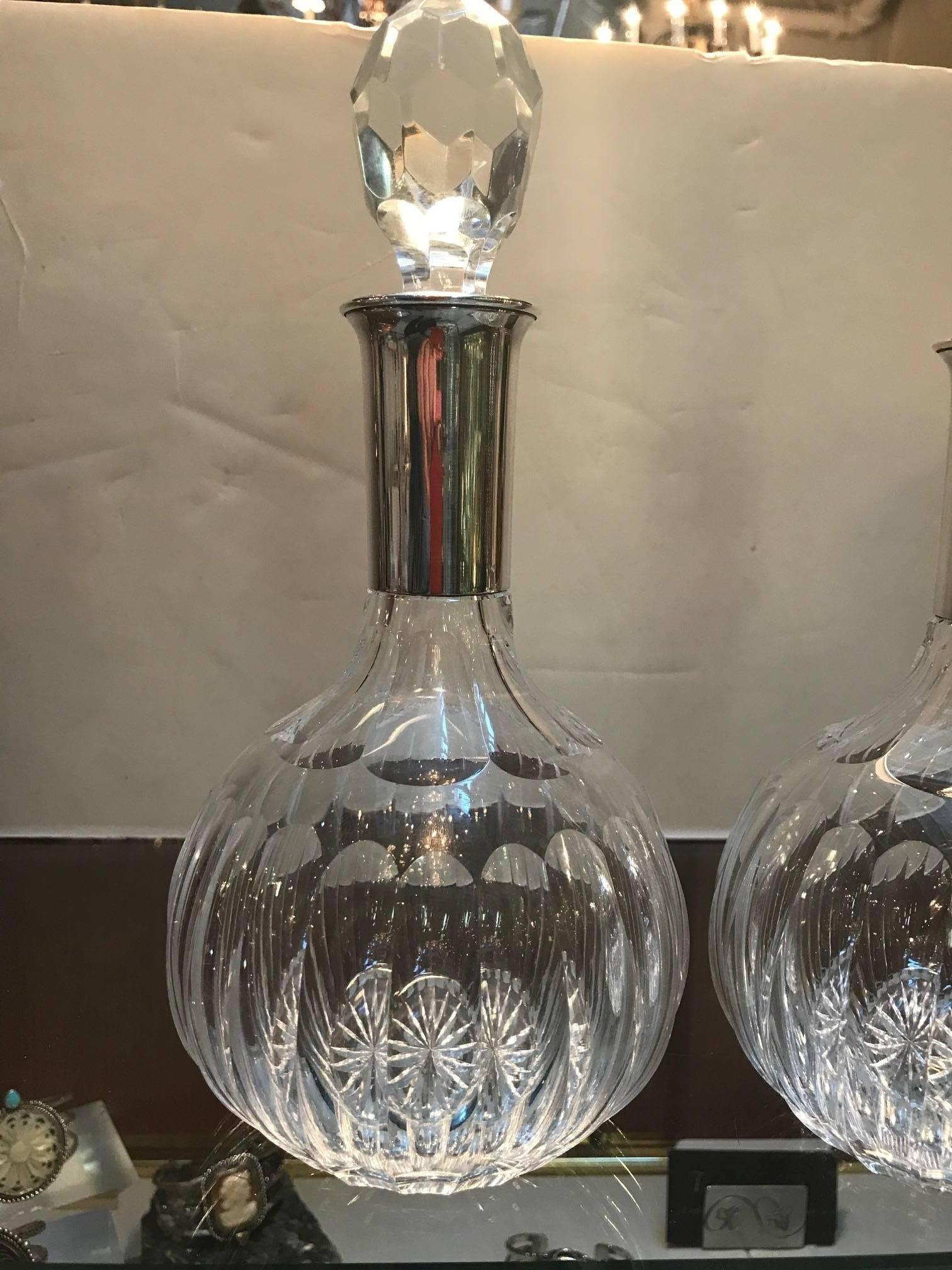 A pair of cut crystal decanters made by Baccarat for Cartier with sterling silver necks. The necks are marked Cartier next to the sterling silver mark which is viewable with a magnifier. Glamorous, mid-20th century decanters made by the best crystal