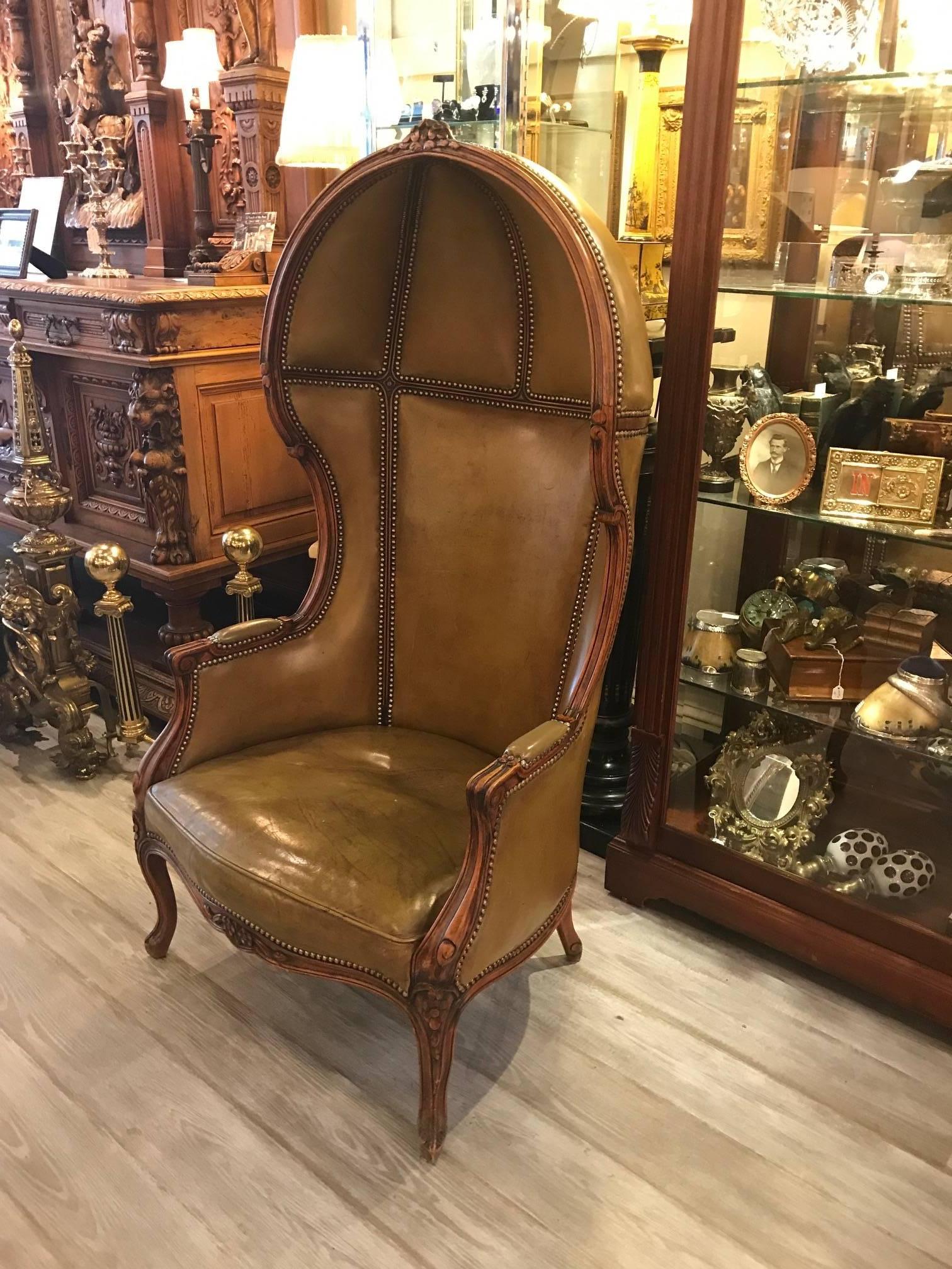 A Louis XV style leather upholstered hand carved beechwood porter chair.
The carved frame with cabriole legs upholstered in olive leather with brass nail head trim.
A porter's chair was a type of chair used in medieval England and later France.