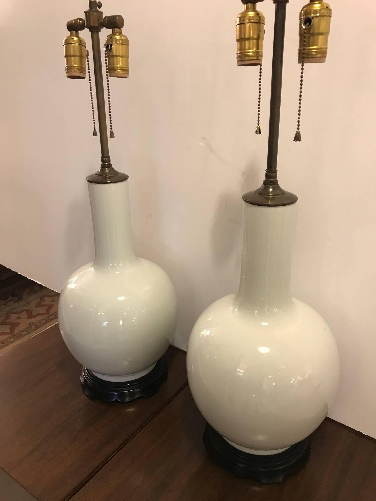Mid-20th century Blanc de Chine porcelain gourd lamps with ebonized wood bases. Antiqued brass hardware with black bases, newly re-wired. The finials are adjustable to go lower than the 31