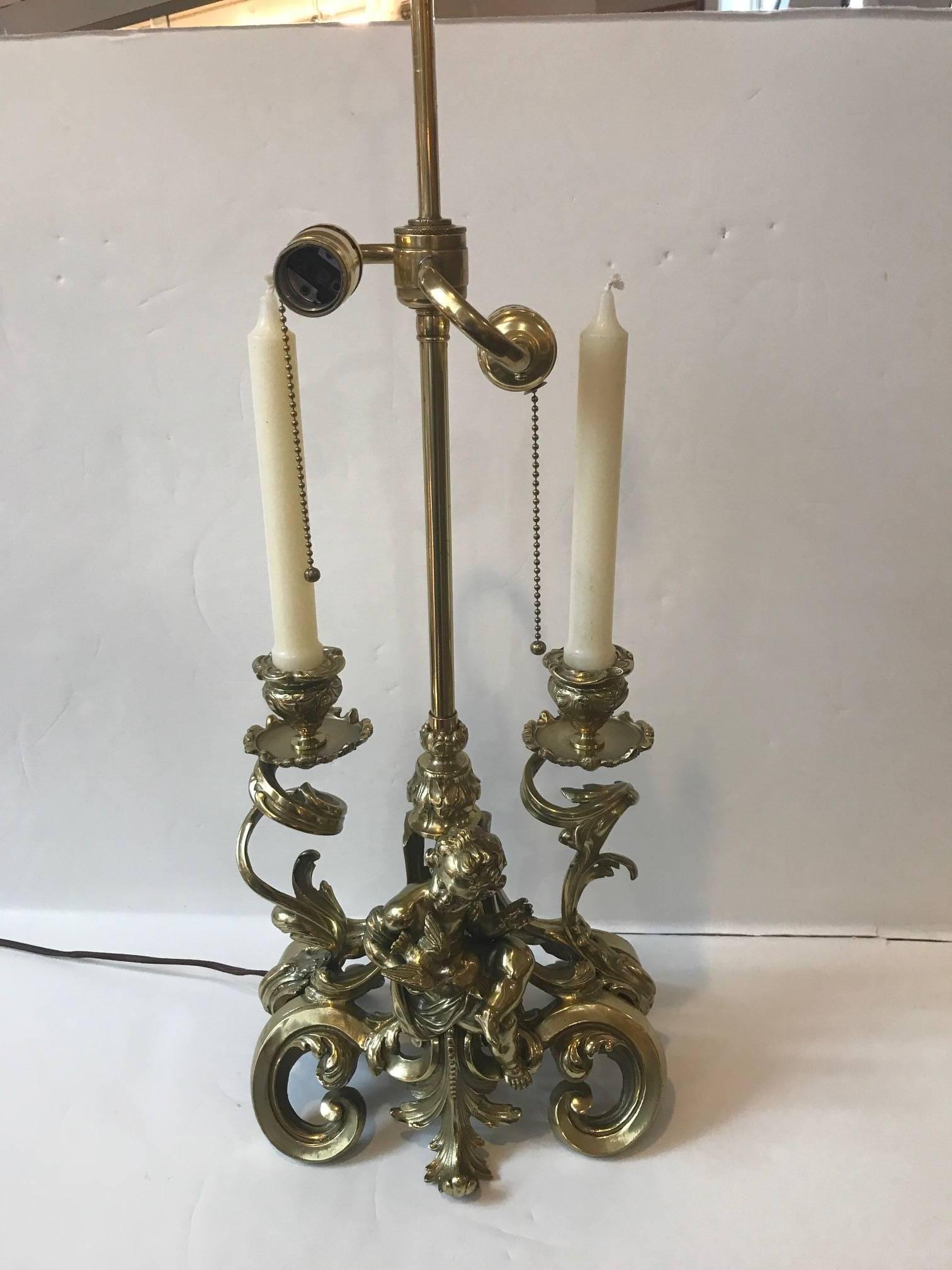 19th century polished bronze candelabra bouillotte lamp. Beautifully cast bronze made in France in the Louis XV style, originally a candle lamp, now electrified. The hand-painted tole shade in an iron red with hand gilt decoration. The central putti