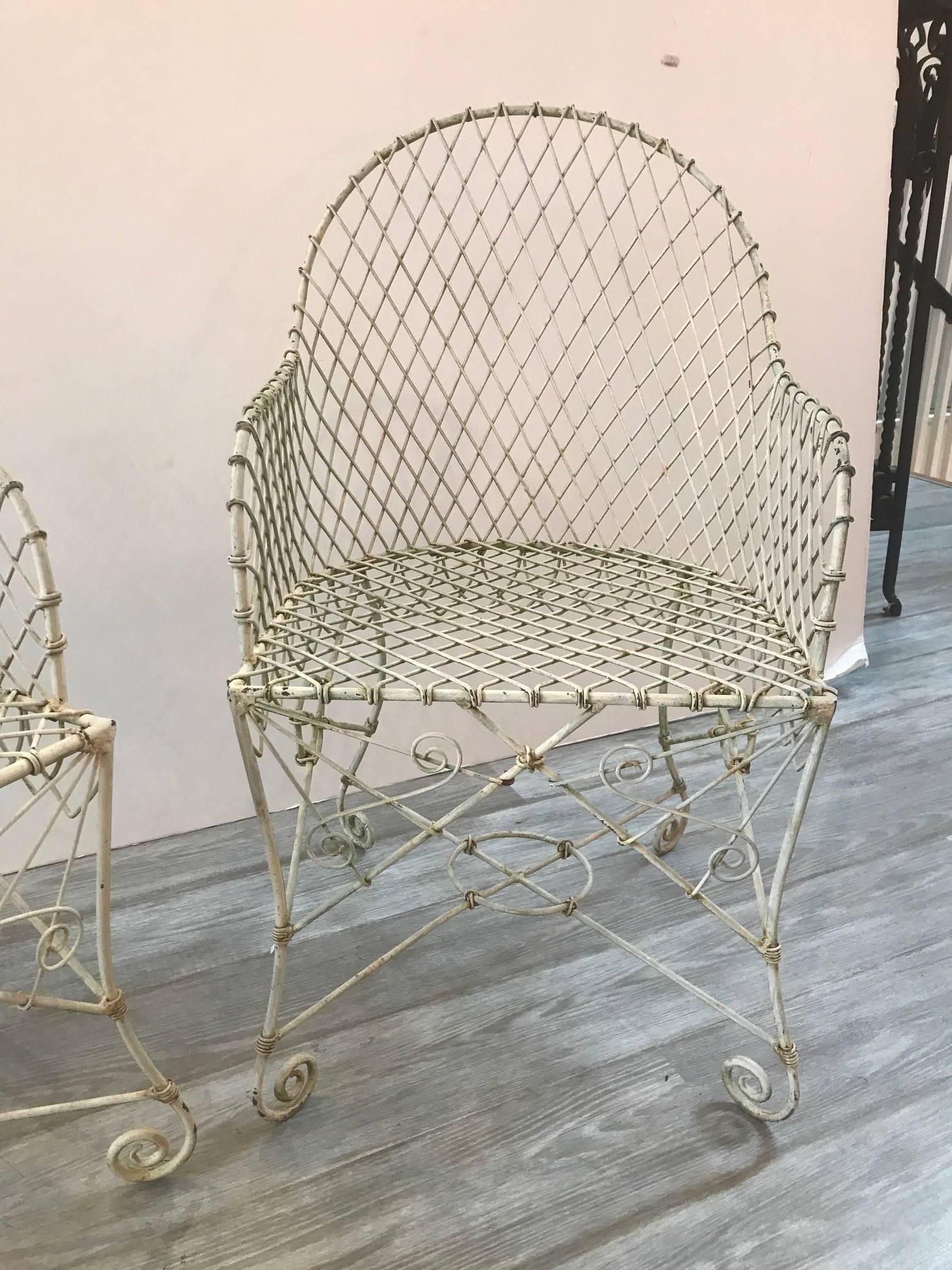 Shapely pair of French wire rounded barrel chairs with painted finish. Sturdy frames and comfortable with or without cushions. The painted finish is weathered and can be repainted or used as is.