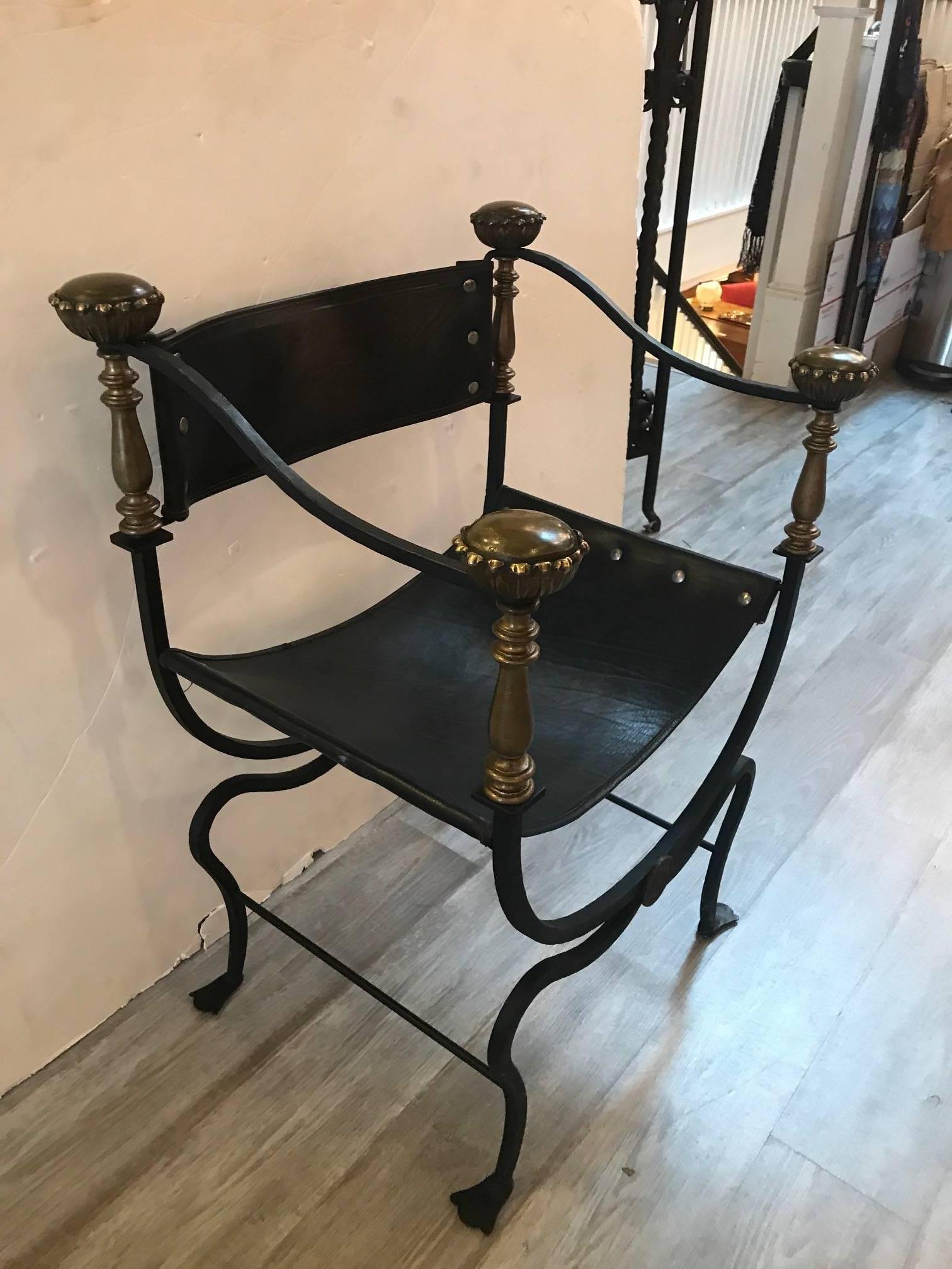 A mid-20th century hand-wrought iron and brass savonarola chair, made in Italy. Of Classic form with large brass finials in each corner. The back and seats are riveted black leather. Solid and sturdy.
