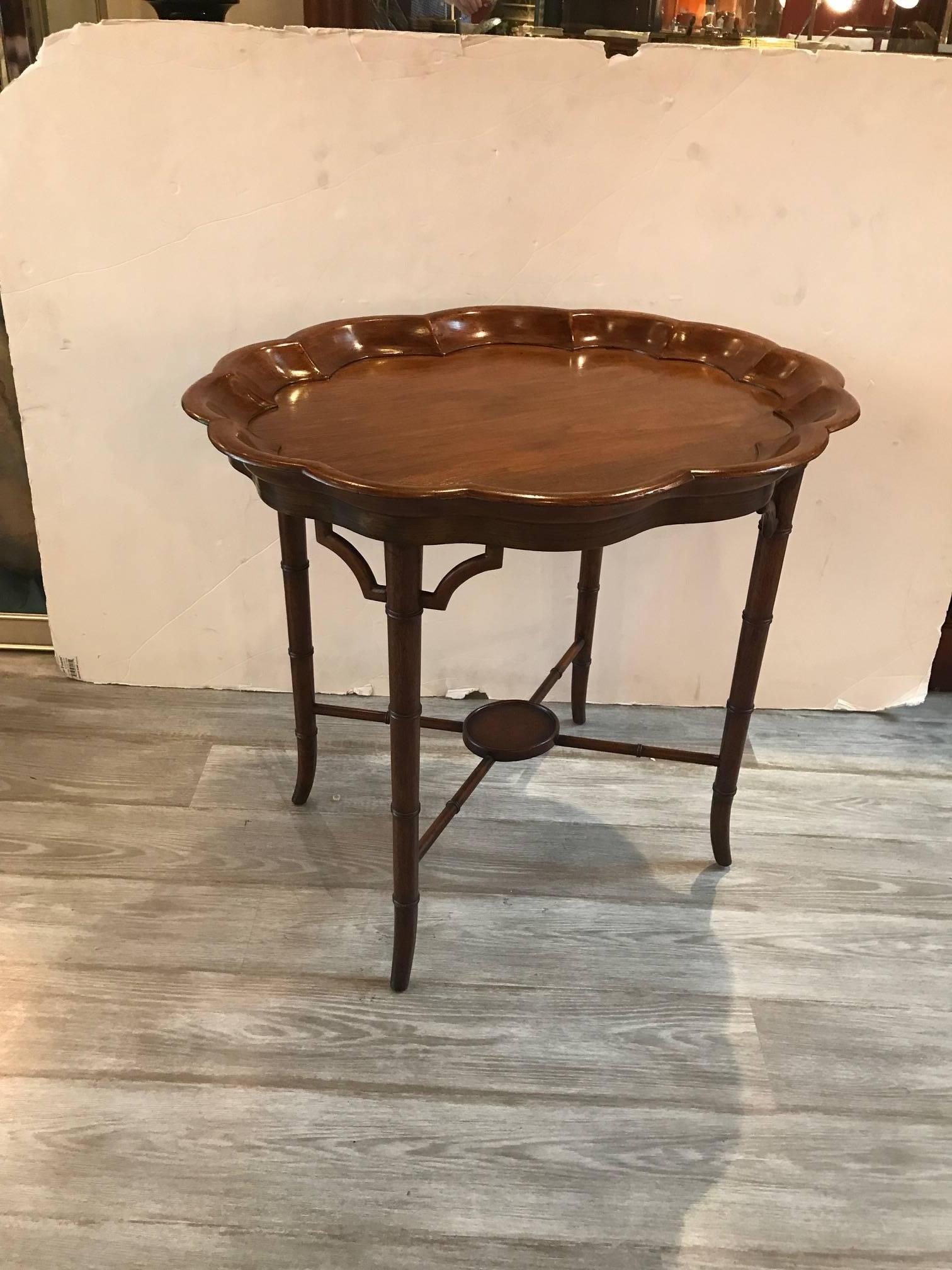 Oval walnut table with deep hand-carved piecrust gallery edge. The warm mellow medium to dark stain with Regency style flared legs and central oval plateau stretcher base. Graceful and elegant.