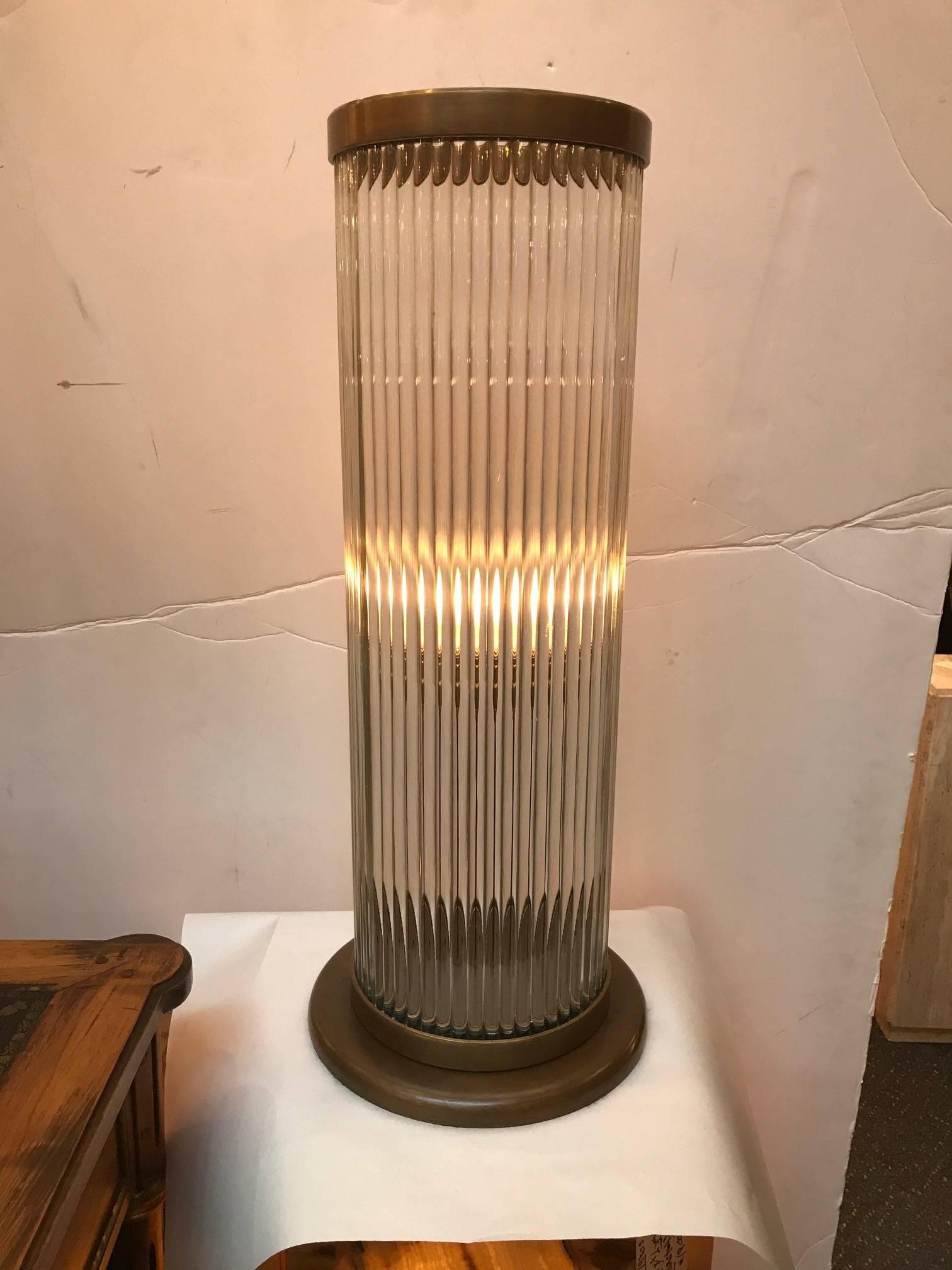 1970s cylindrical glass lamp with bronze mounts. The tall glass body with ribbed exterior and 10.5 inch bronze base. The top has a diameter of 8.25 inches. Takes a standard bulb with low, medium and high setting. Deco inspired design.