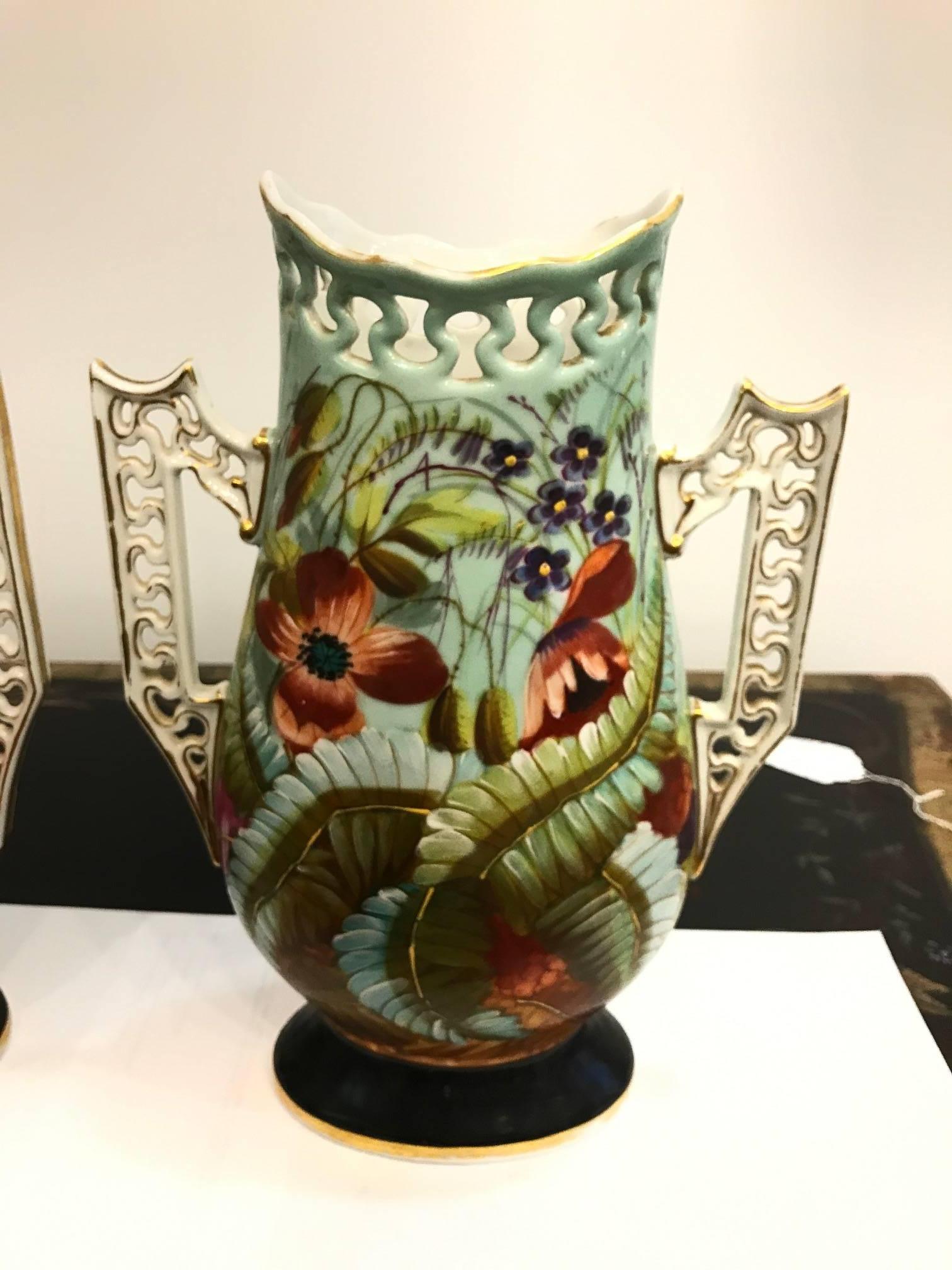 Vibrant pair of Old Paris porcelain botanical vases. Each one hand-painted and are a mirror image of each other. The reticulated handles have gilt decoration and the piercings match along the tops of the vases.
