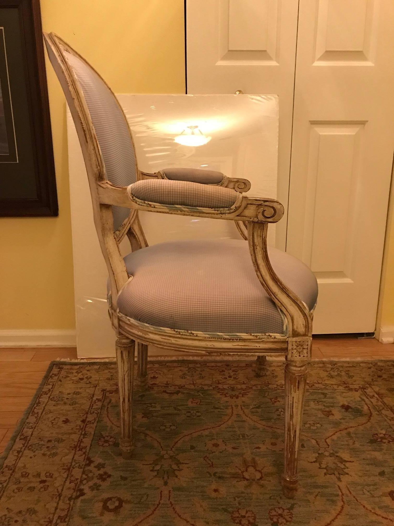 A pair of French carved painted walnut Louis XVI style chairs by Maison Jansen. 
The classic frames with oval backs padded arms and hand tied coil spring seats with original cream beige paint with an overall distressed finish The fabric is silk and